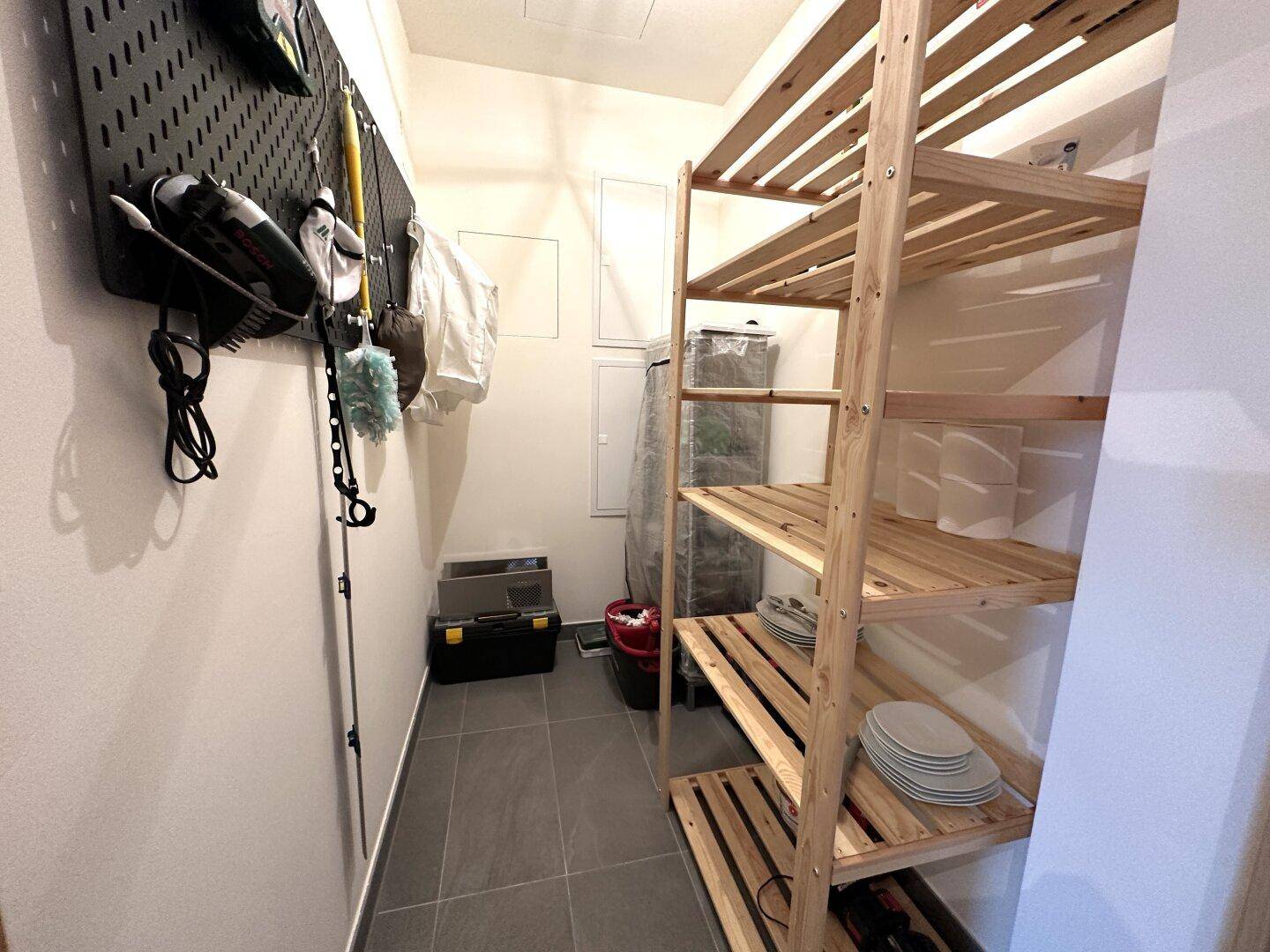 Praktischer Abstellraum mit Holzregalen und Stauraum für Haushaltsgegenstände.