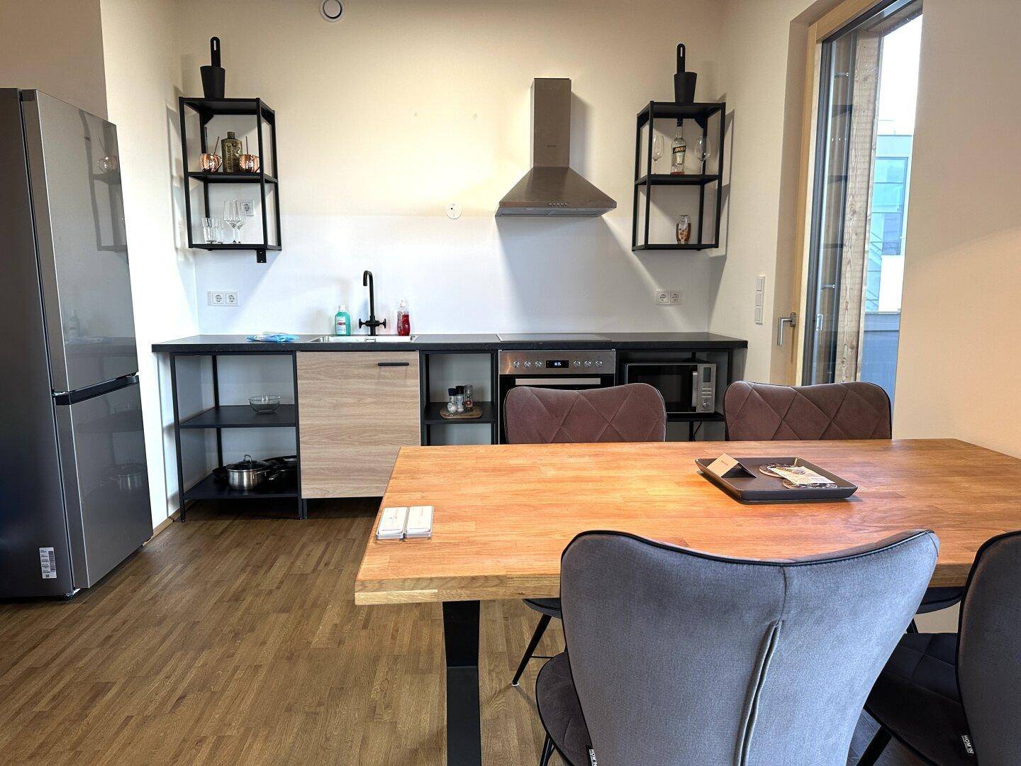 Offene Küche mit Holzboden, modernen schwarzen Arbeitsplatten und integrierten Geräten.
