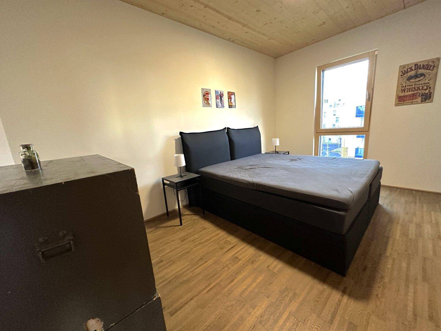 Schlafzimmer mit Doppelbett, Holzboden und großem Fenster für viel Tageslicht.