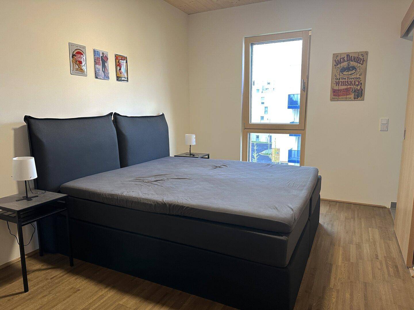 Modernes Schlafzimmer mit Holzboden, bequemen Bett und Fenster mit Blick nach draußen.