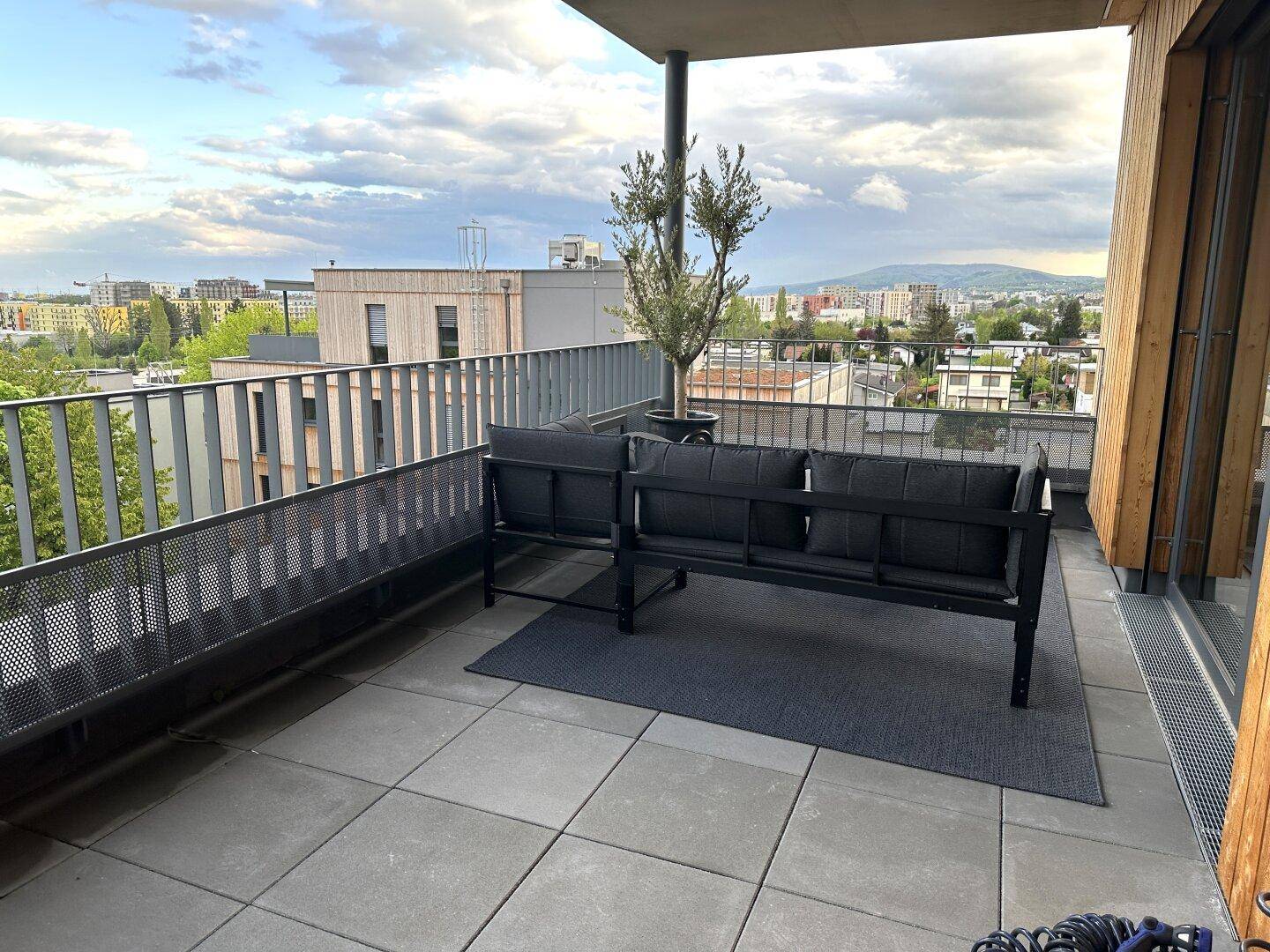 Geräumige Terrasse mit modernen Outdoor-Möbeln und weitem Blick über die Stadt und Berge.