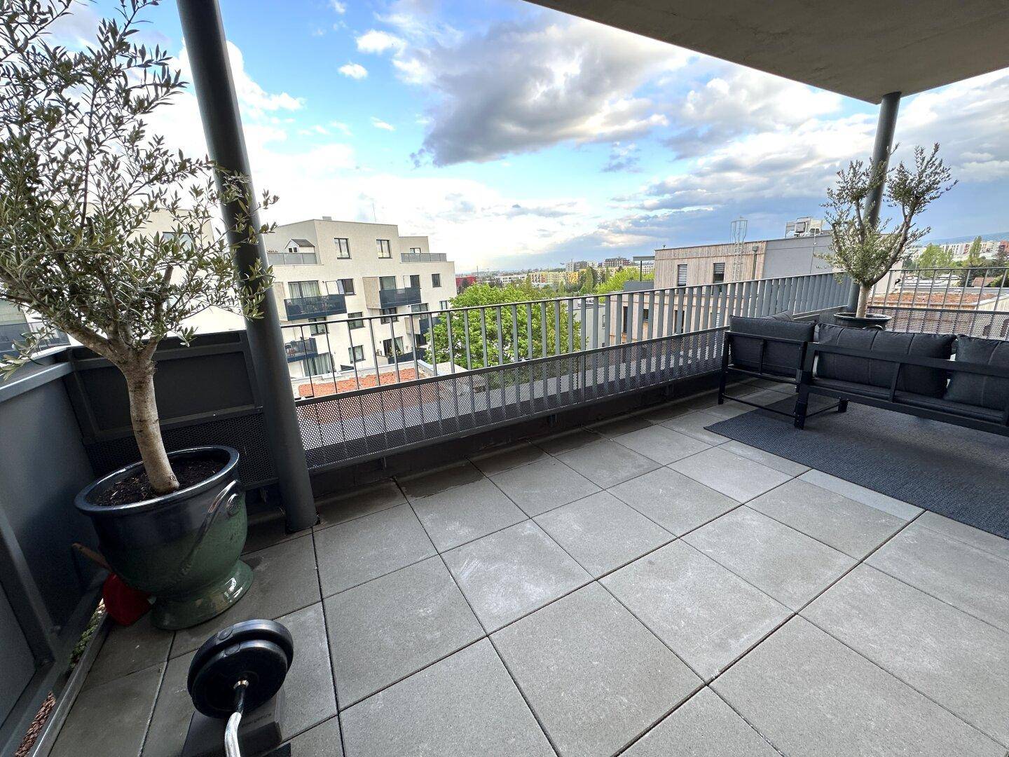 Große Terrasse mit Fliesenboden, Topfpflanzen und Panoramablick auf die Umgebung.