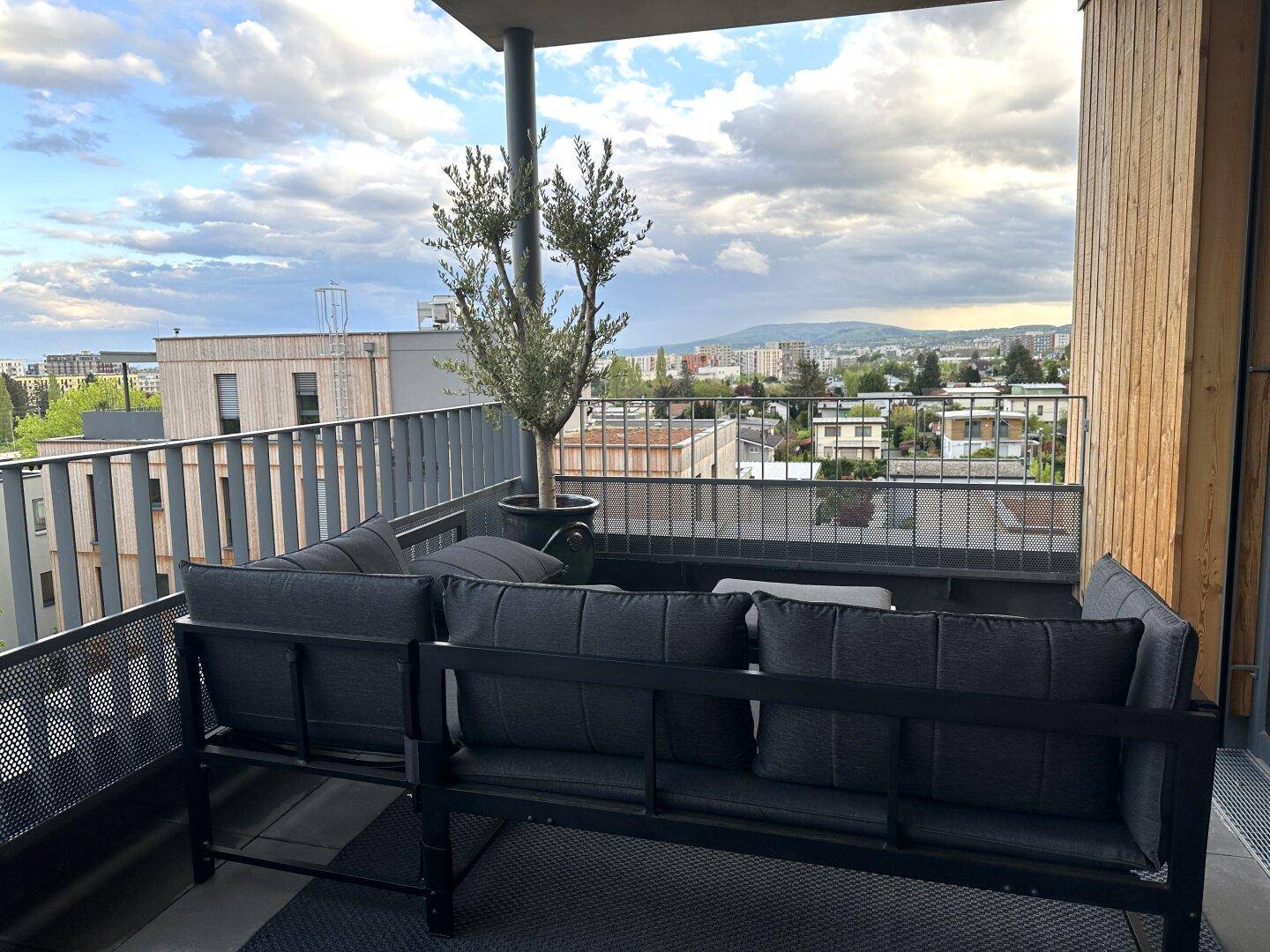 Gemütliche Terrasse mit bequemen Outdoor-Möbeln und einem schönen Ausblick auf die Stadt.