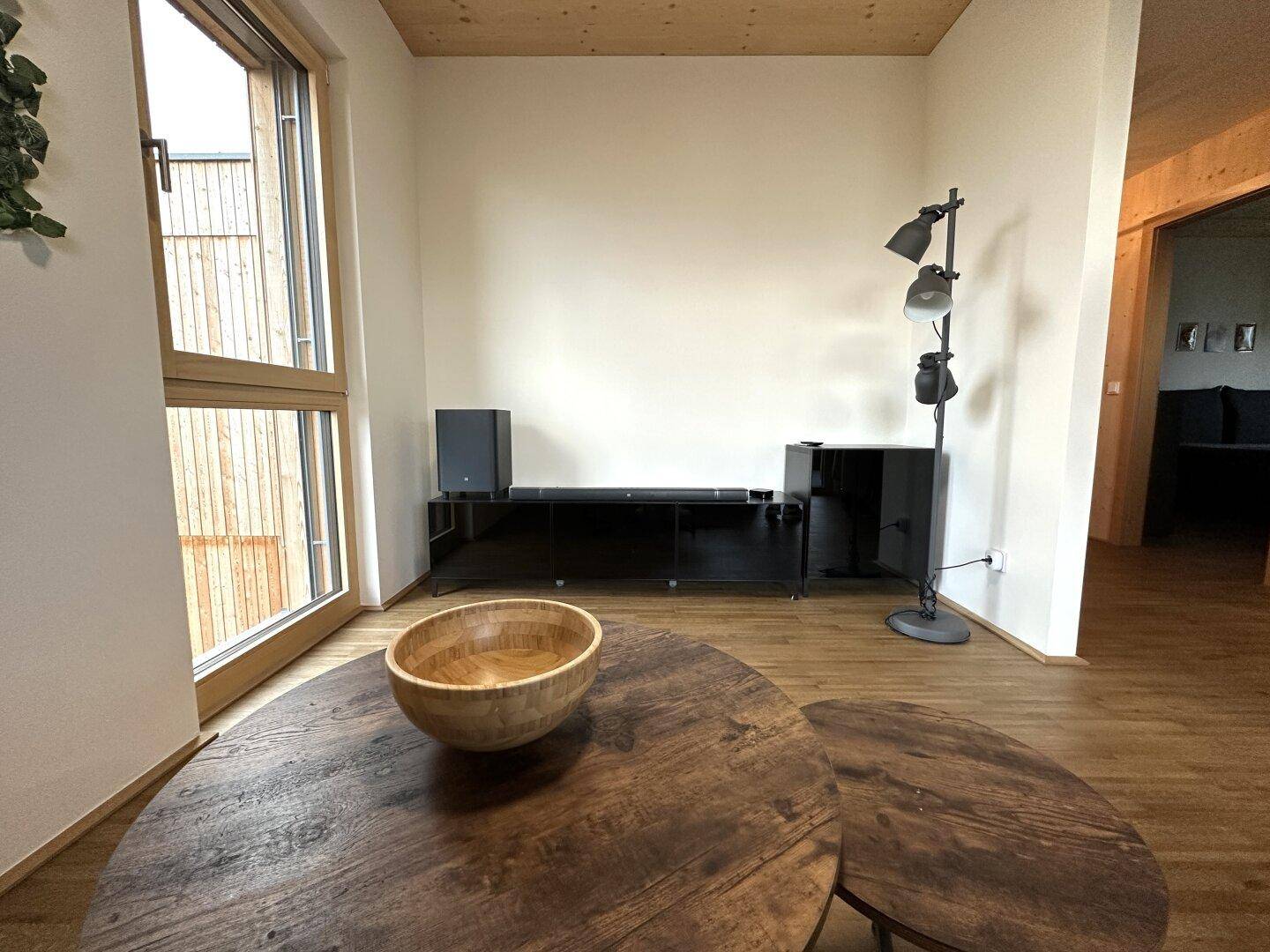Heller Wohnbereich mit Holzboden, modernen Möbeln und großem Fenster für viel Tageslicht.