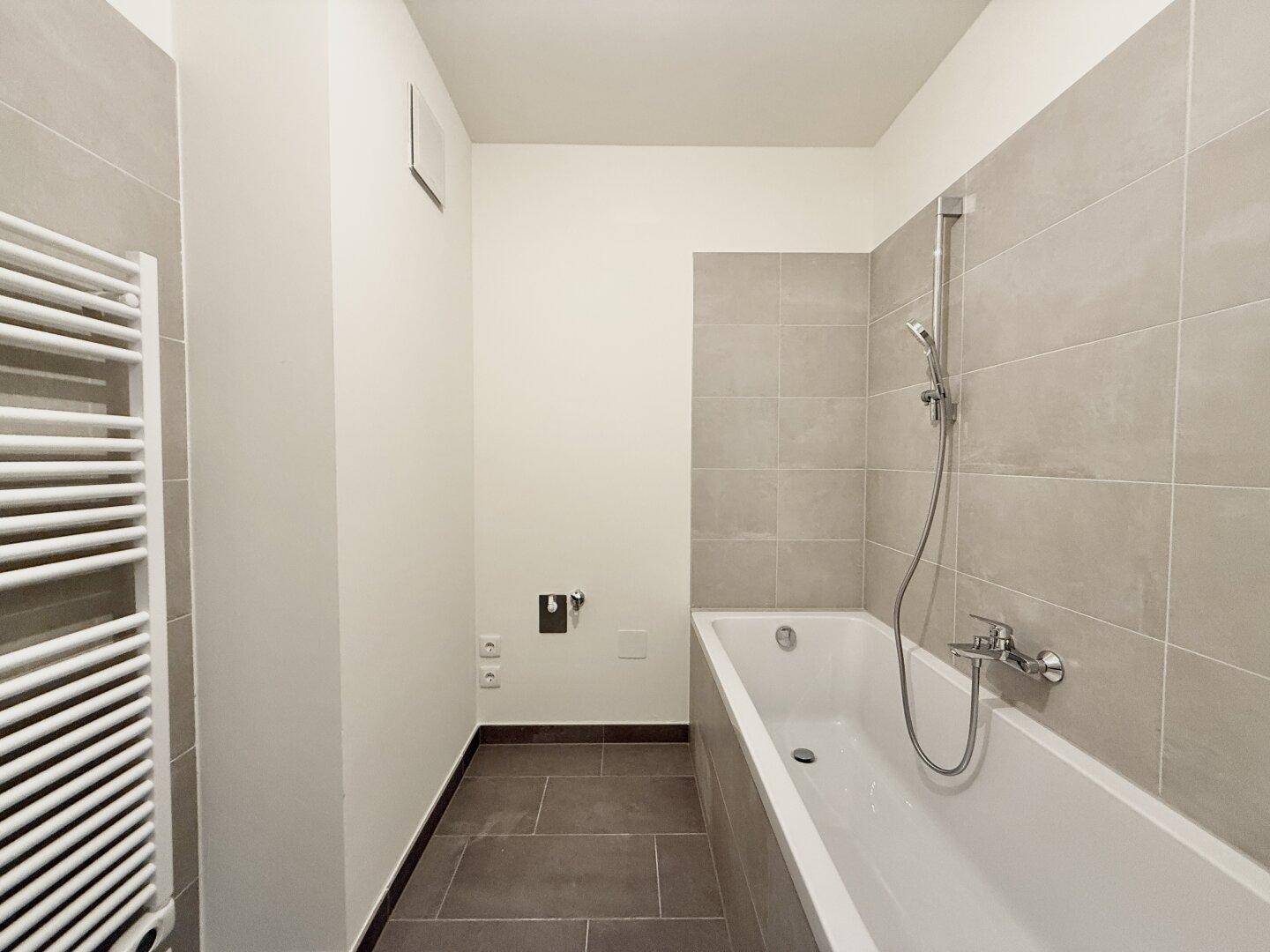 Helles Badezimmer mit Badewanne und modernen Fliesen, bereit für die Nutzung.