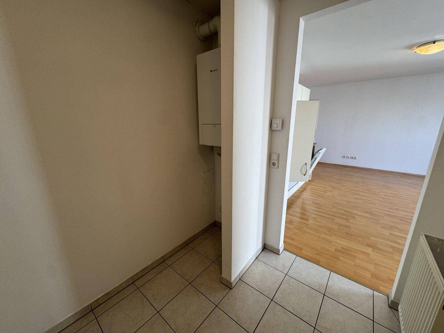 Gefliester Eingangsbereich mit Heizungsanlage und Zugang zum offenen Wohnbereich.