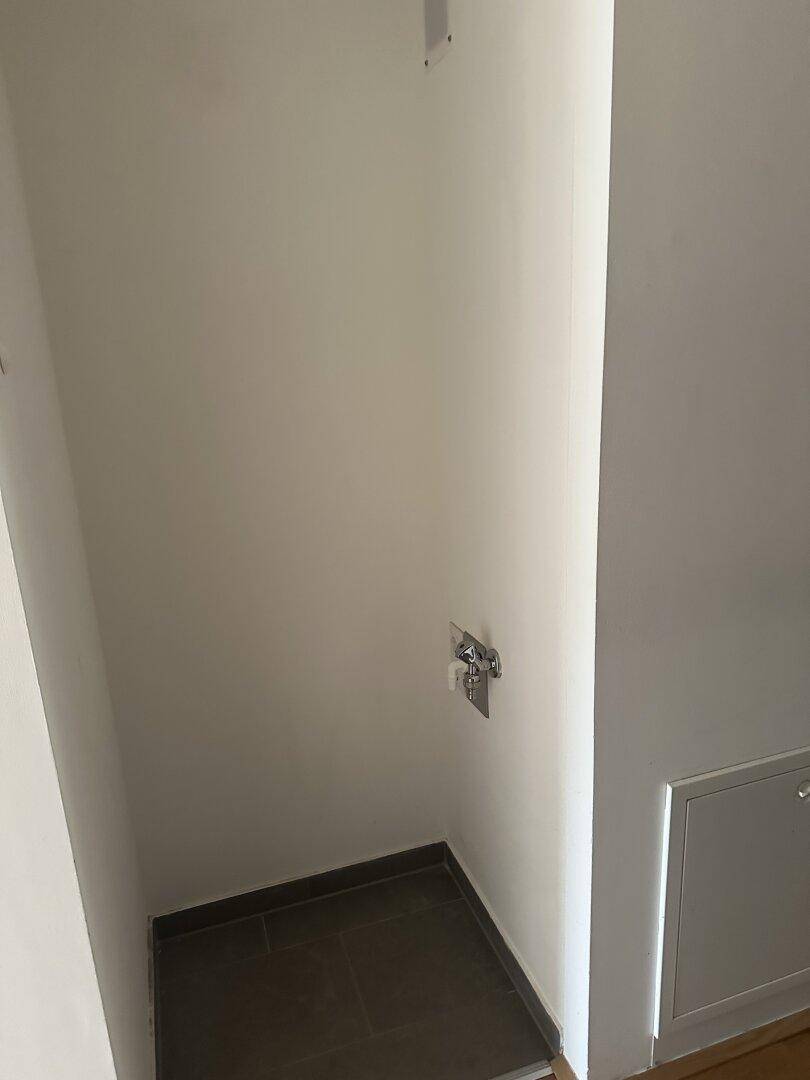 Praktischer Hauswirtschaftsraum mit Fliesenboden und Wasseranschluss, ideal für Waschmaschine oder Lagerung.