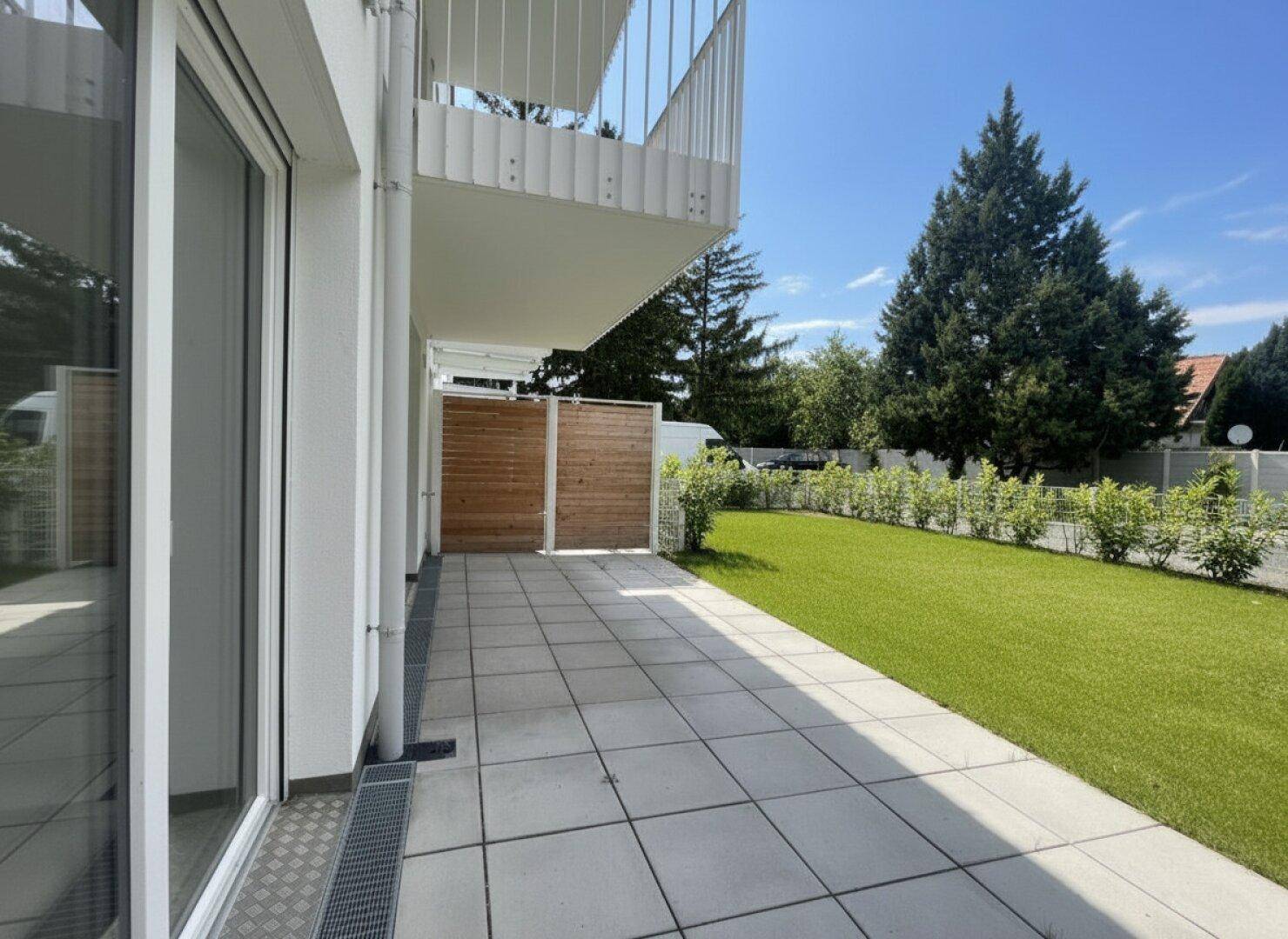 Geräumige Terrasse mit Zugang zum Garten und moderner Gebäudefassade.