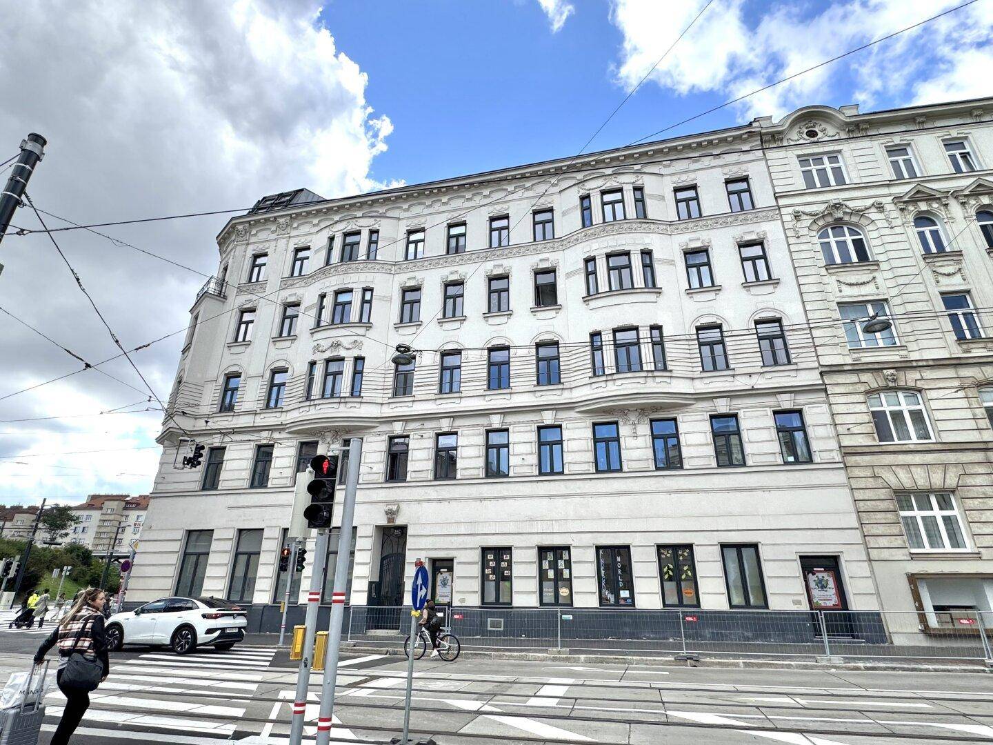 Historisches Eckgebäude mit klassischer, reich verzierter Fassade und vielen Fenstern an einer belebten Stadtstraße.