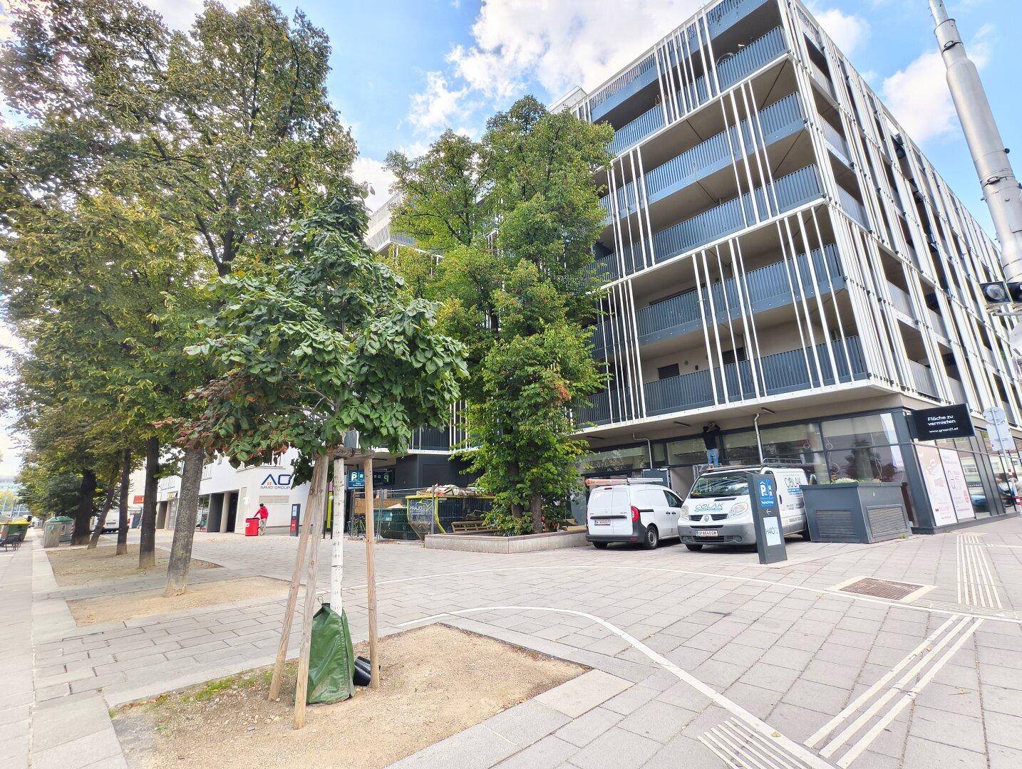 Moderne Gebäudefassade mit großen Fenstern und Balkonen an einer städtischen Straße.