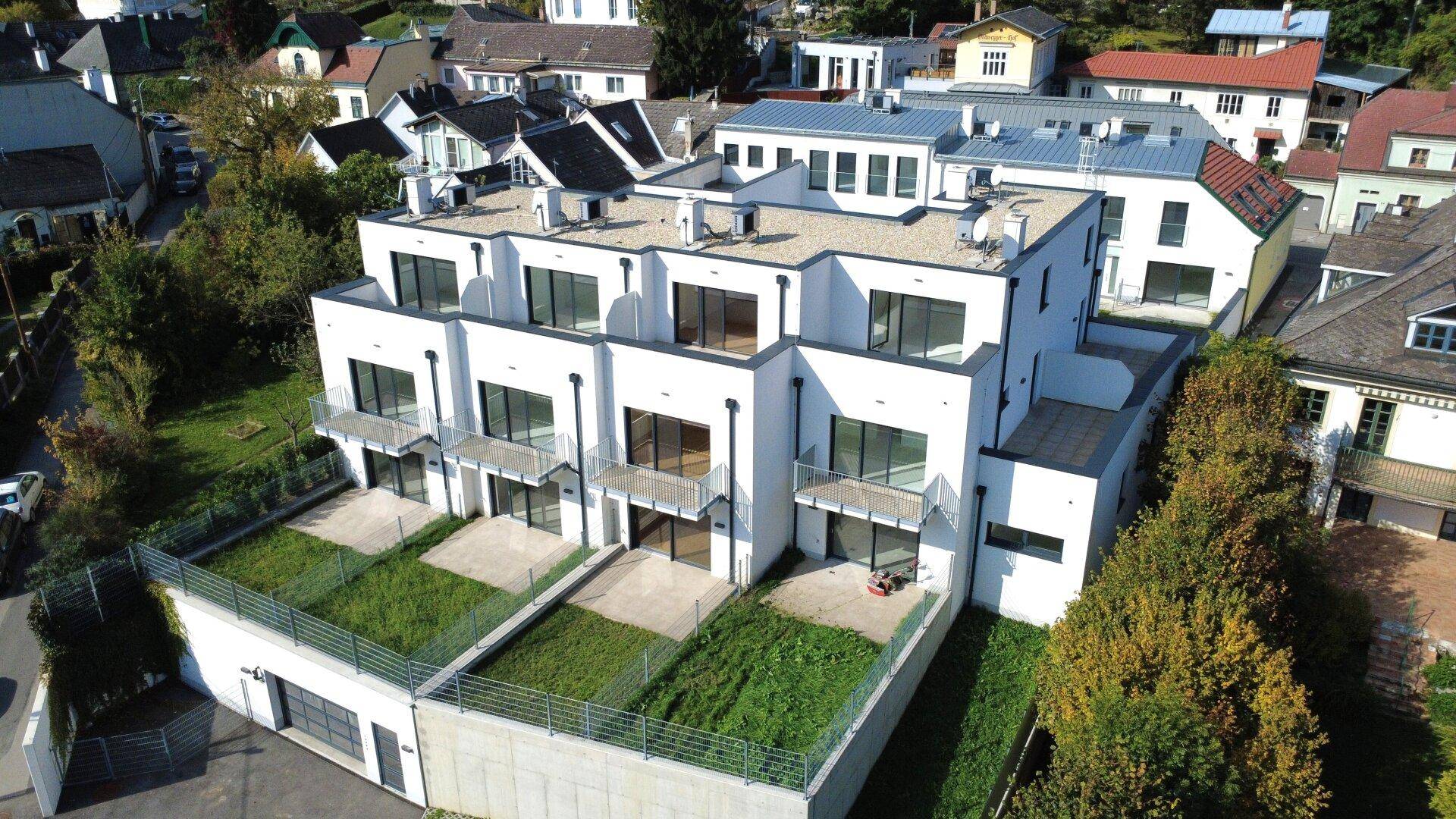 Ansicht einer zeitgenössischen Wohnanlage mit klaren Linien, großen Fenstern und privaten Terrassenbereichen.