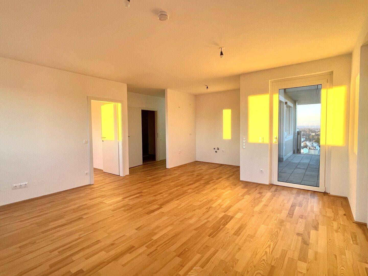 Geräumiger, heller Raum mit Parkettboden und Zugang zu weiteren Zimmern sowie einem Balkon.