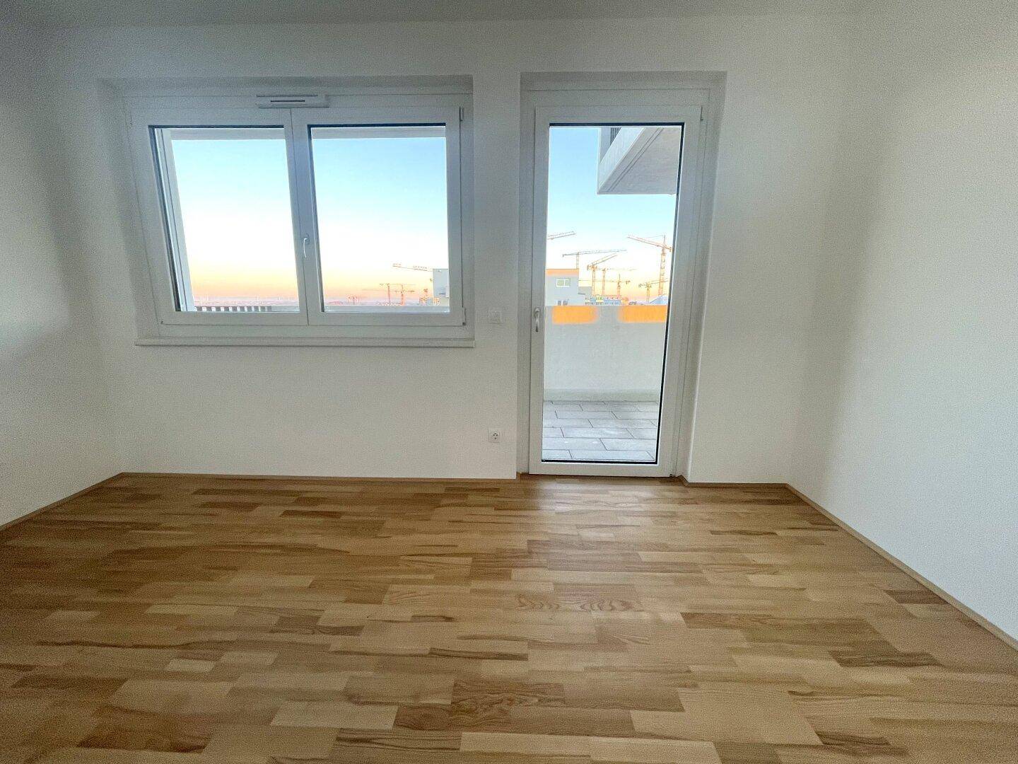 Heller Raum mit Parkettboden und Zugang zu einem Balkon, ideal als Schlaf- oder Arbeitszimmer.