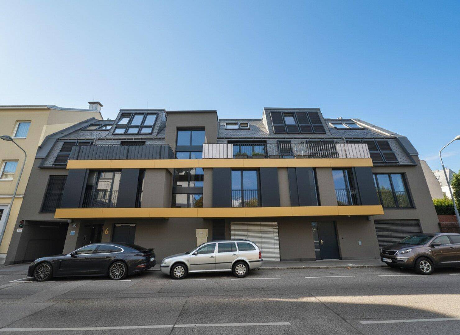 Moderne Wohnhausfassade mit großen Fenstern, Balkonen und zeitgenössischer Architektur.