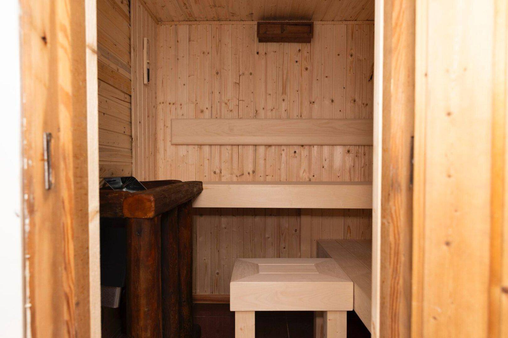 Gemütliche Holzsauna mit mehreren Sitzebenen und traditionellem Saunaofen.
