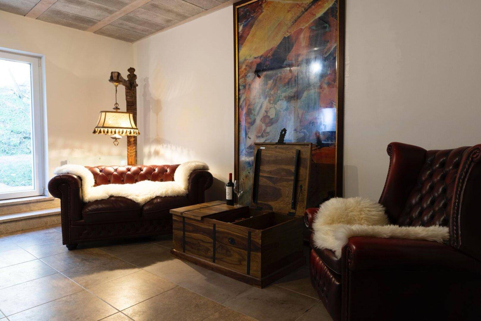 Gemütlicher Wohnbereich mit Ledersofas, Holztruhe und dekorativer Stehlampe.