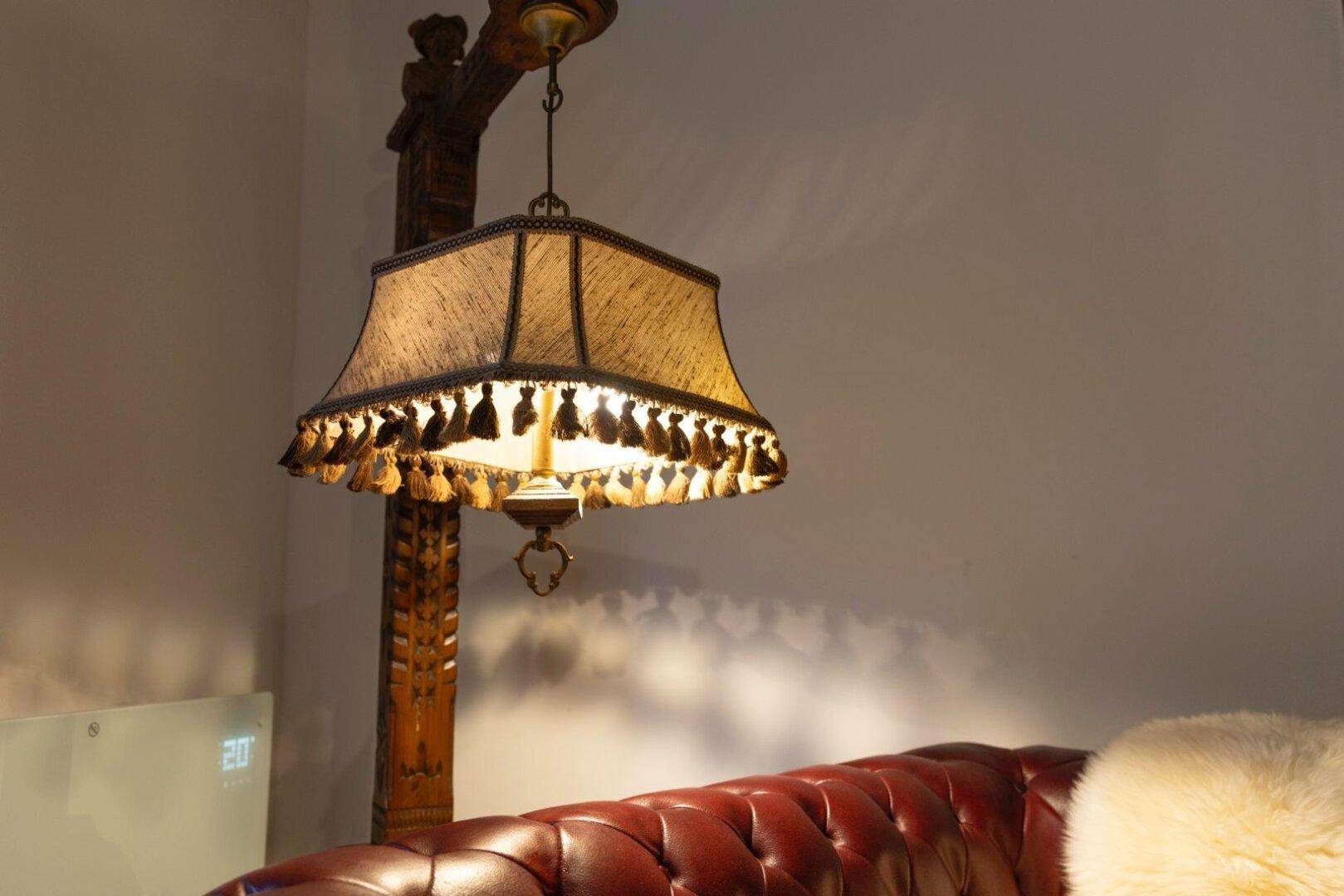 Dekorative Stehlampe mit Fransen und warmem Licht im Wohnbereich.