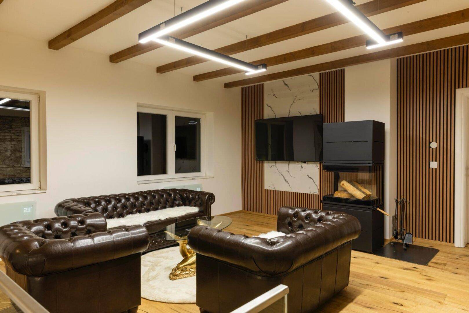 Gemütliches Wohnzimmer mit Ledersofas, Holzboden und modernem Kaminofen.