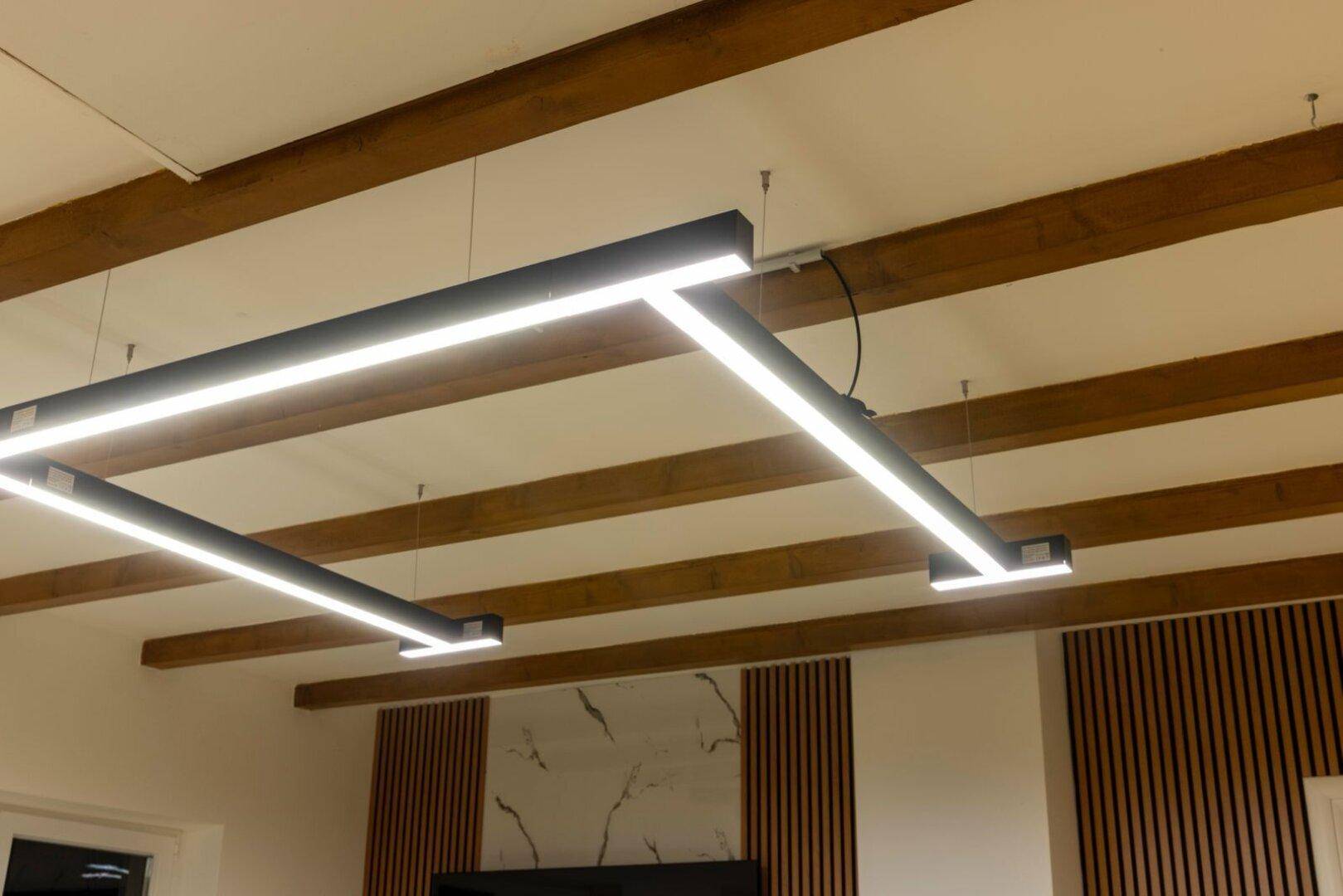 Moderne Deckenbeleuchtung mit LED-Streifen und freiliegenden Holzbalken.