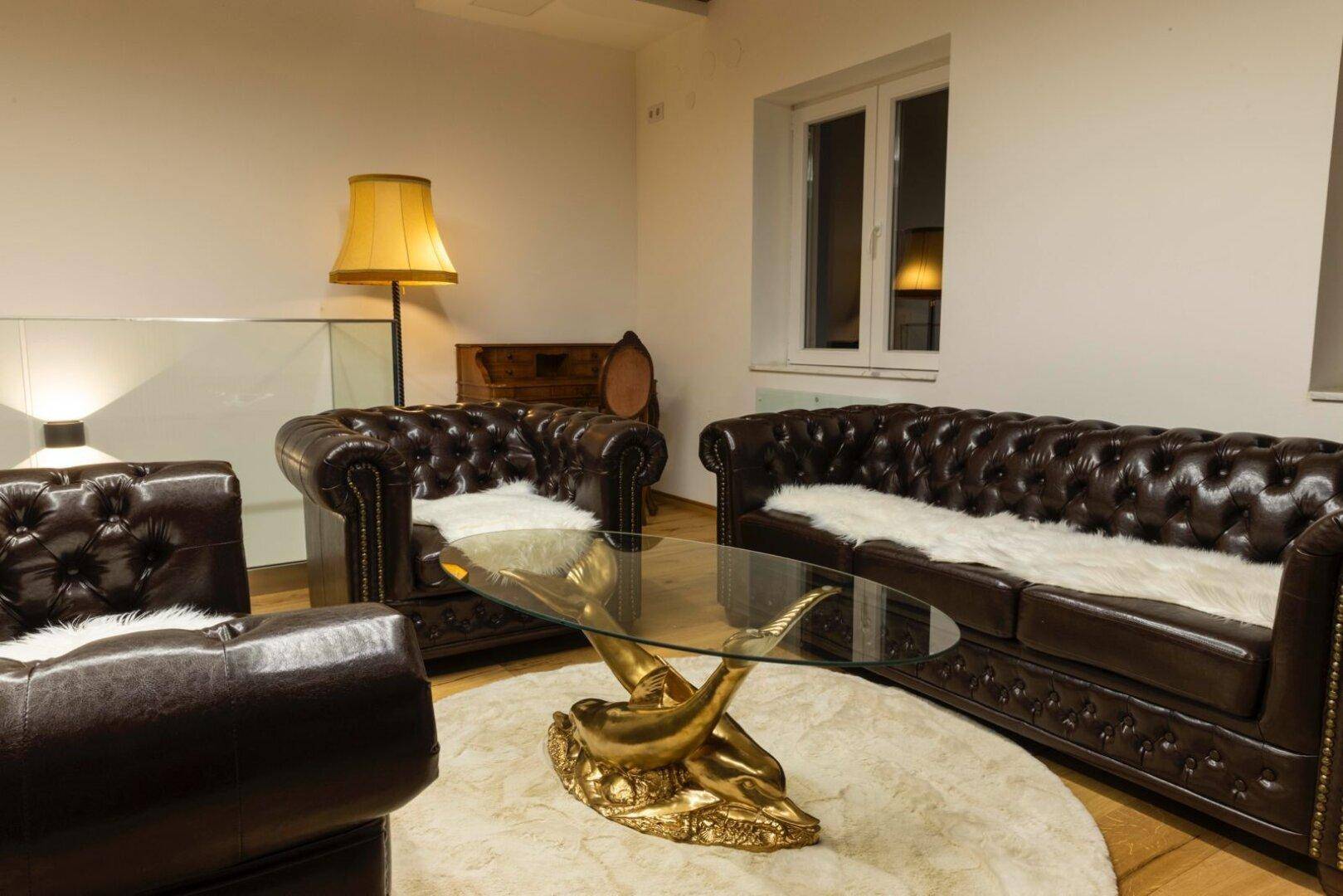 Gemütliche Sitzecke mit Ledersofas, Couchtisch und Stehlampe.