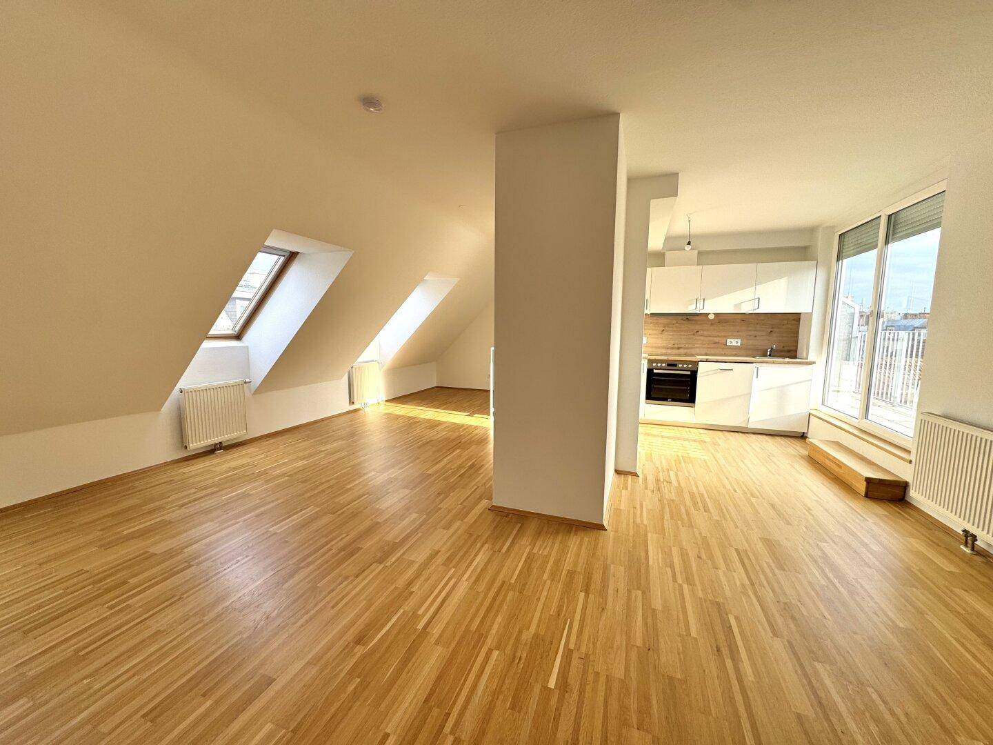 Offener Wohnbereich mit Küche, Holzboden, Dachfenstern und viel Tageslicht.