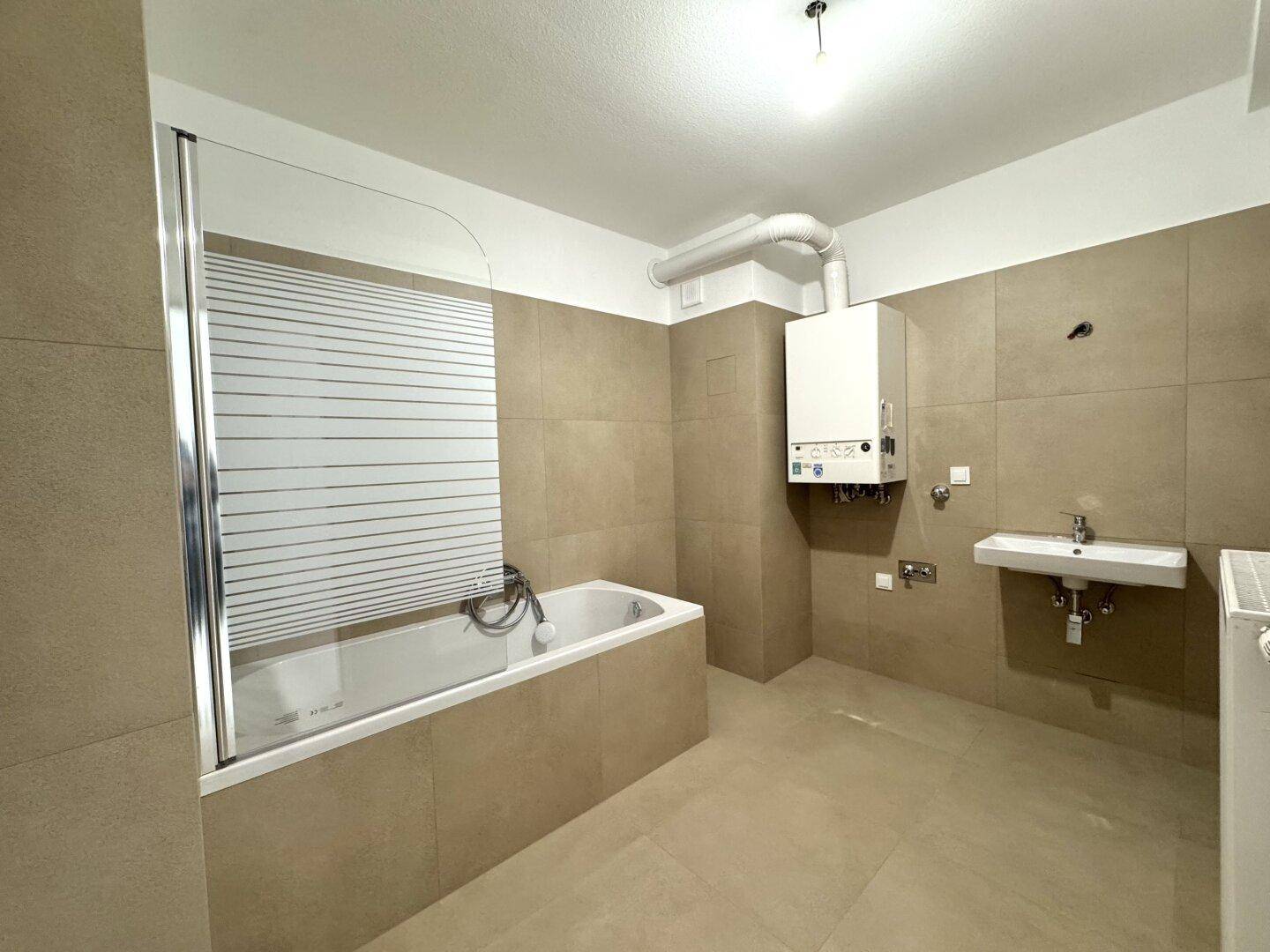 Modernes Badezimmer mit Badewanne, Dusche und beigefarbenen Fliesen, in gutem Zustand.