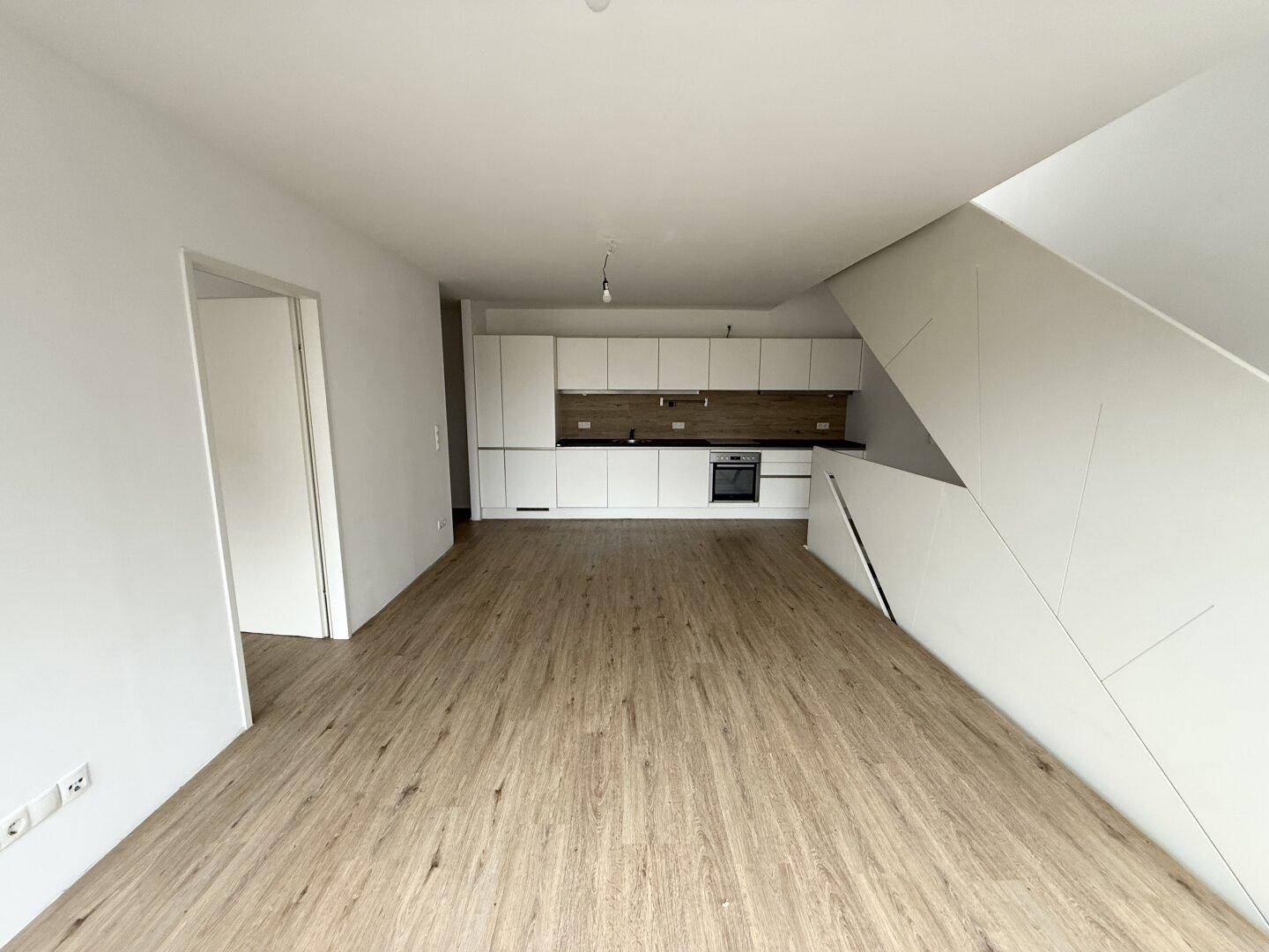 Geräumiger Wohn- und Essbereich mit offener Küche und Zugang zur Treppe in die obere Etage.