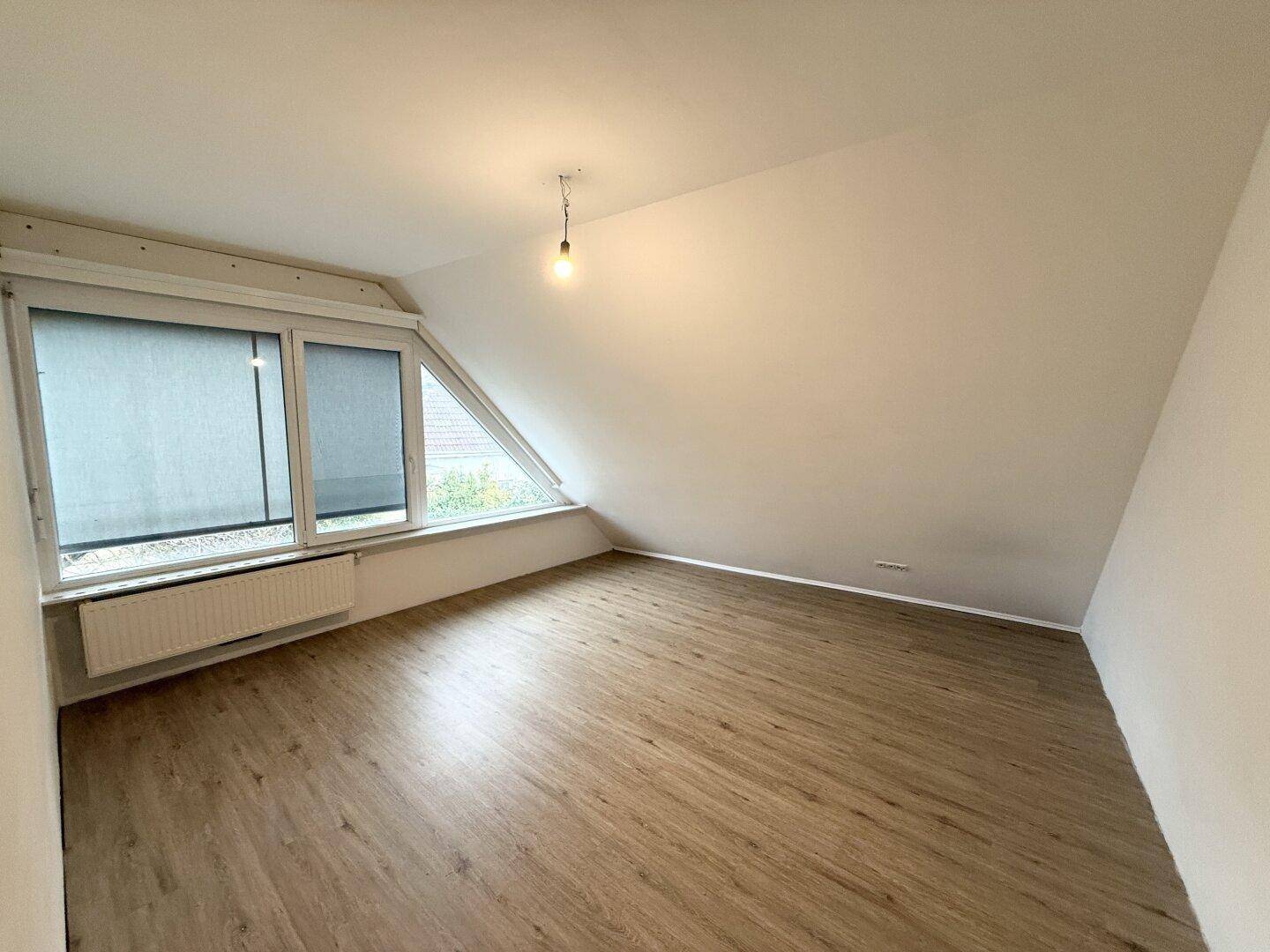 Geräumiges Dachzimmer mit Laminatboden und schrägen Wänden, ideal als Schlaf- oder Arbeitszimmer.