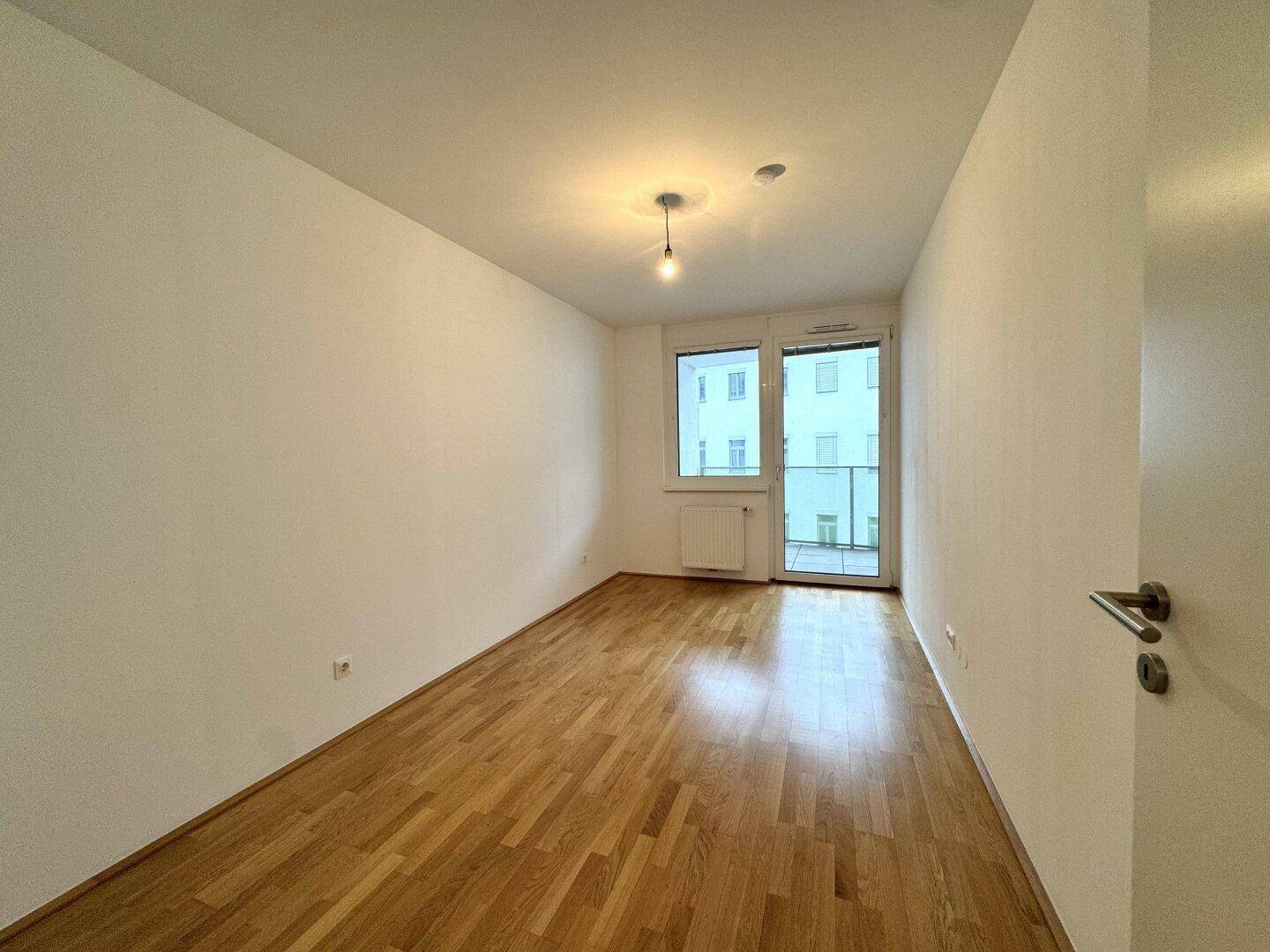 Helles Schlafzimmer mit Parkettboden und direktem Zugang zum Balkon.