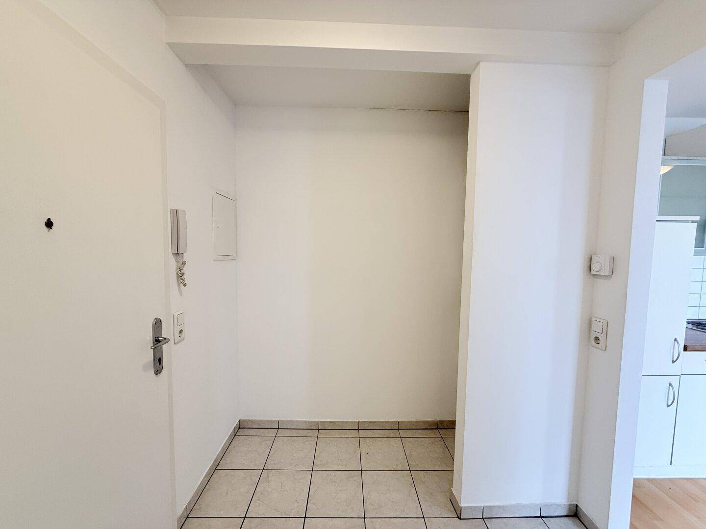 Eingangsbereich mit hellen Fliesen und einer Nische, ideal für Garderobe oder Stauraum.
