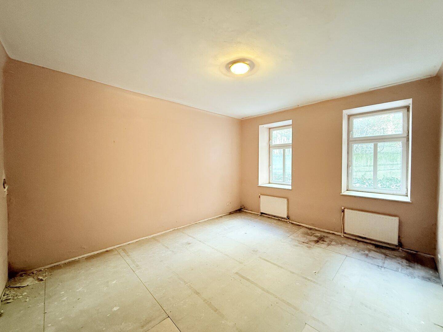 Helles Wohnzimmer mit zwei Fenstern und neutralen Wänden, ideal für eine moderne Einrichtung.