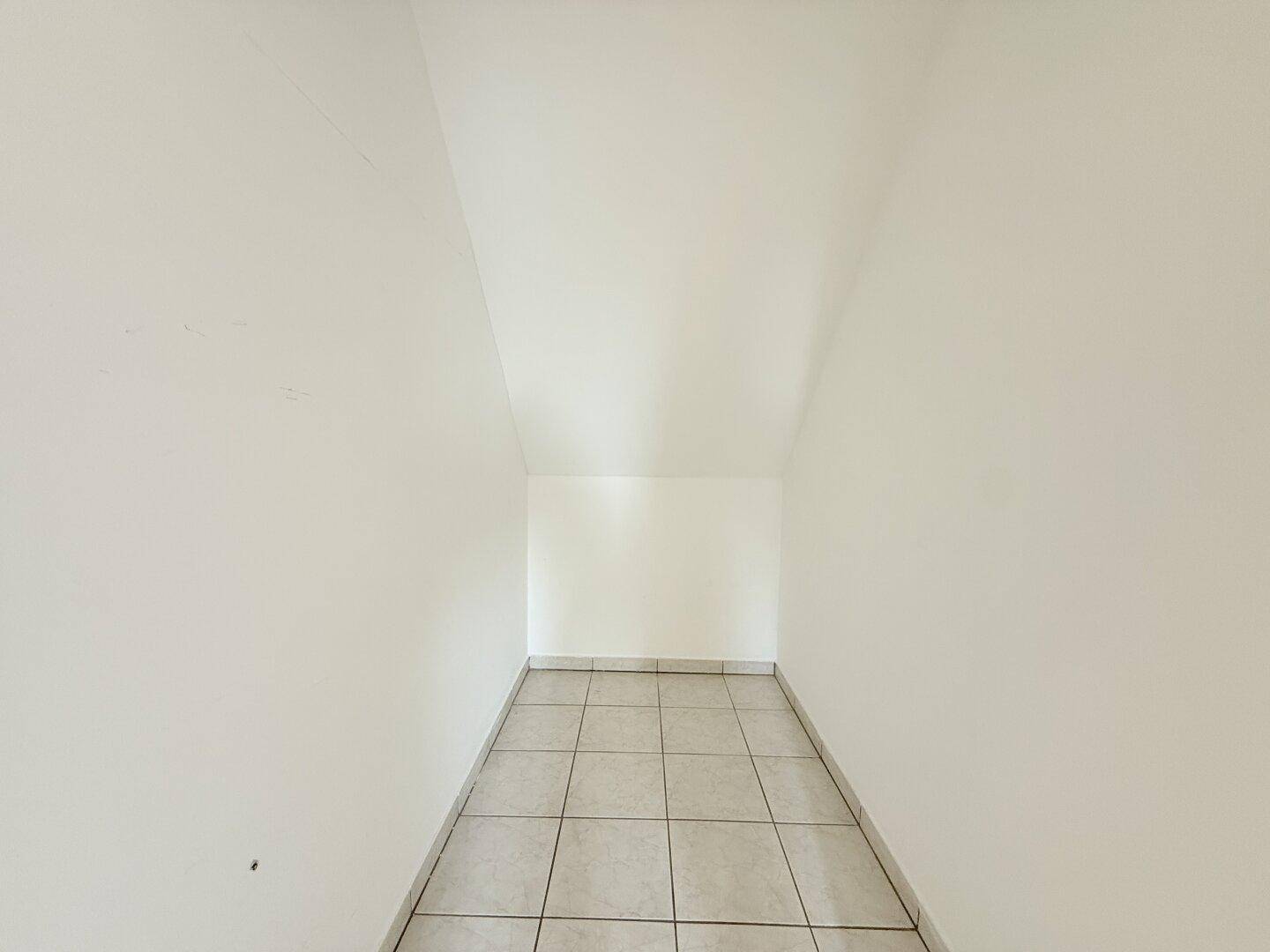 Praktischer Abstellraum mit Fliesenboden und Dachschräge für zusätzlichen Stauraum.