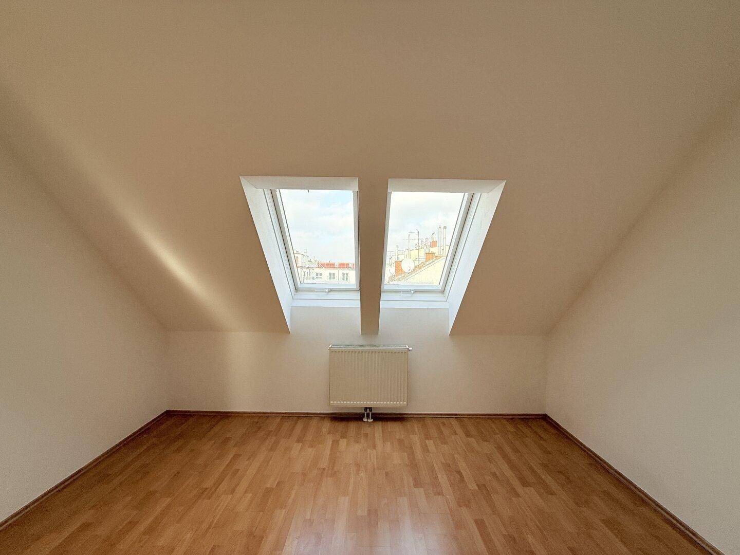 Geräumiges Zimmer mit zwei großen Dachfenstern und Blick nach draußen.