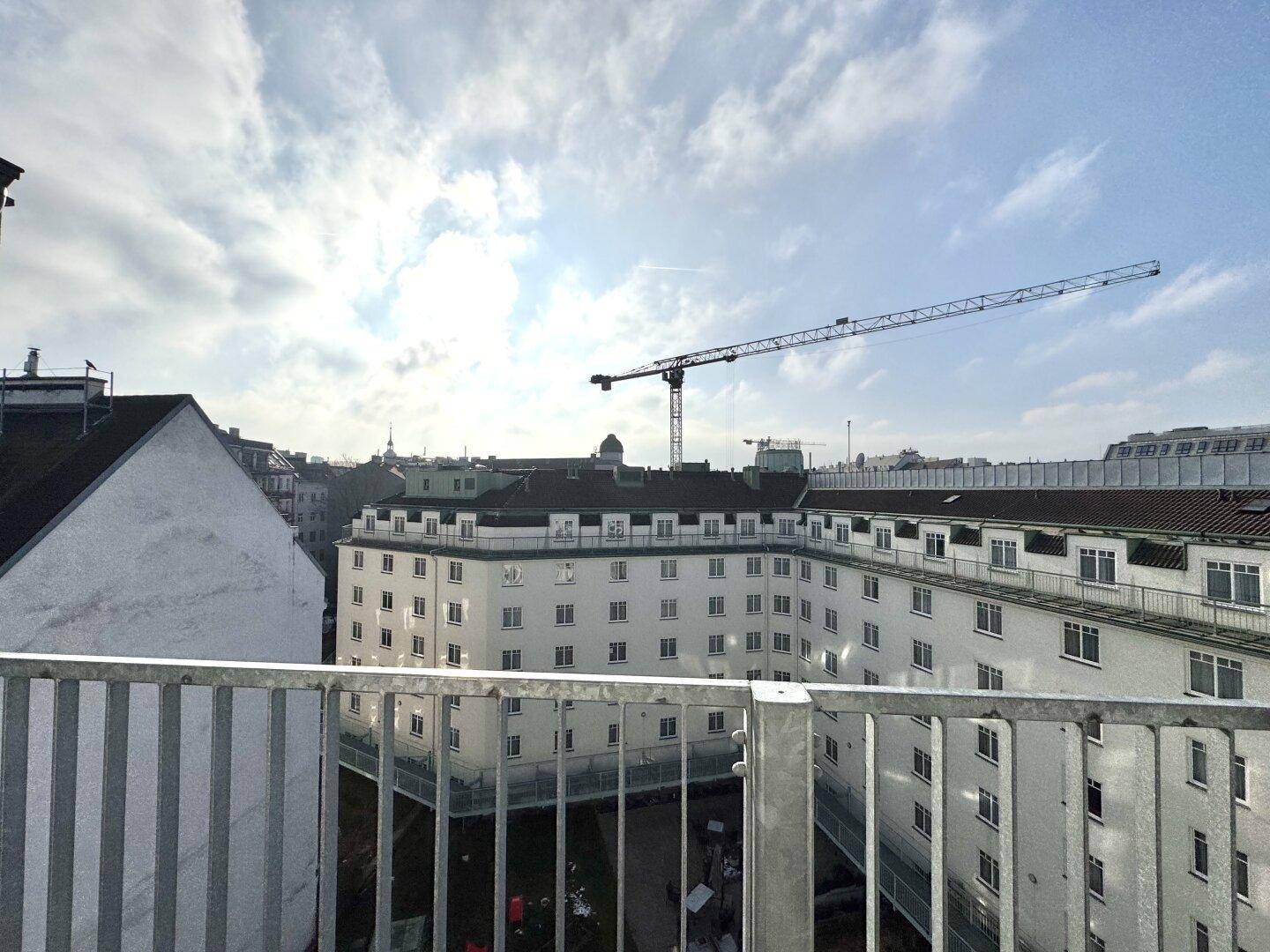 Weiterer Blick vom Balkon auf den Innenhof und die umliegenden Gebäude mit Baukran.