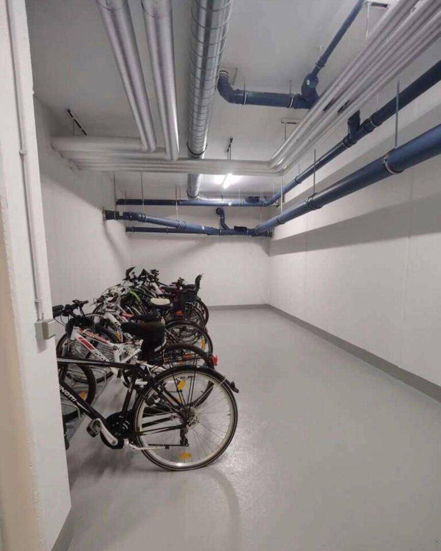 Fahrradraum im Untergeschoss mit mehreren Fahrrädern und sichtbaren Versorgungsleitungen.