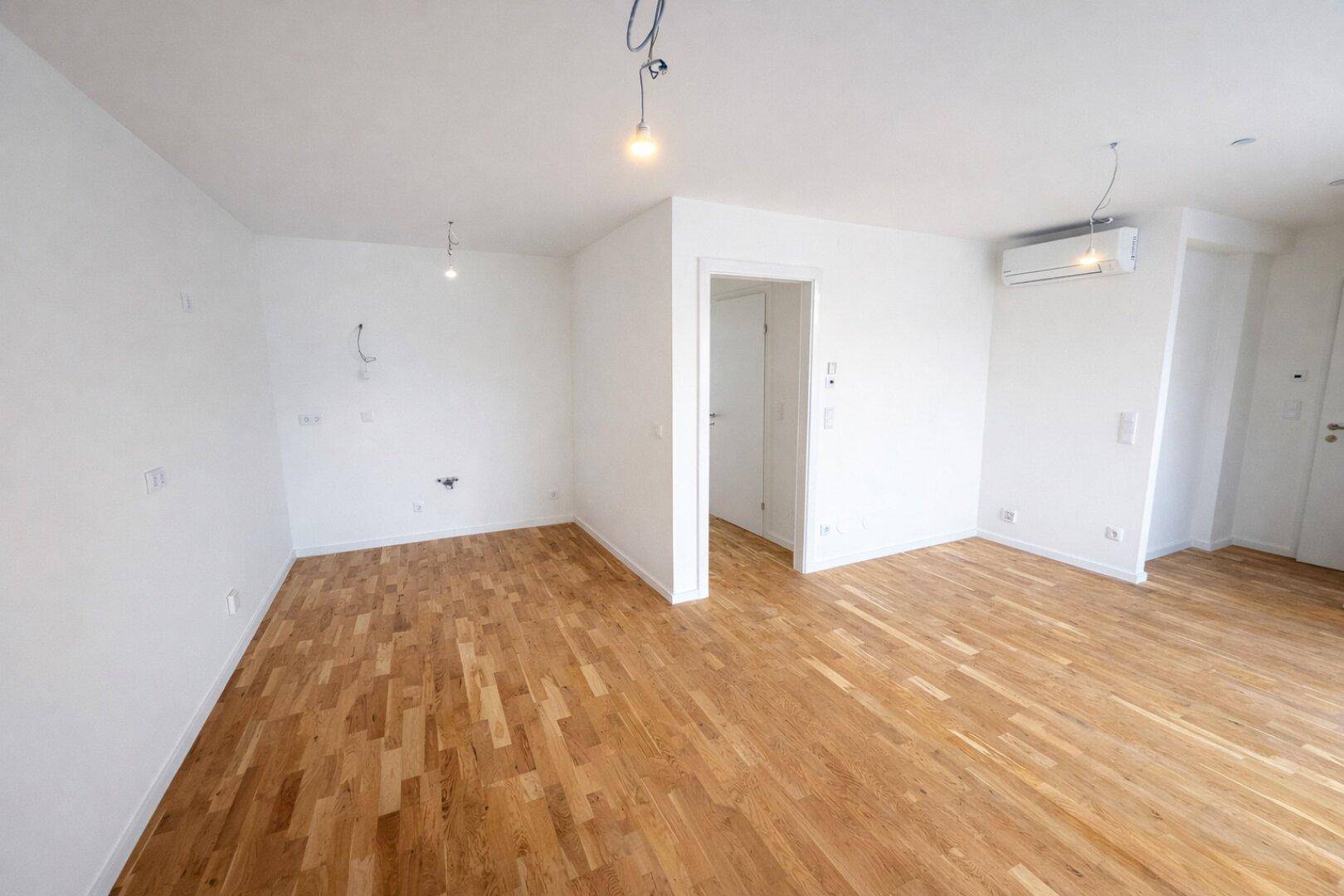 Geräumiges, helles Wohnzimmer mit Parkettboden und Klimaanlage, bereit zum Einzug.