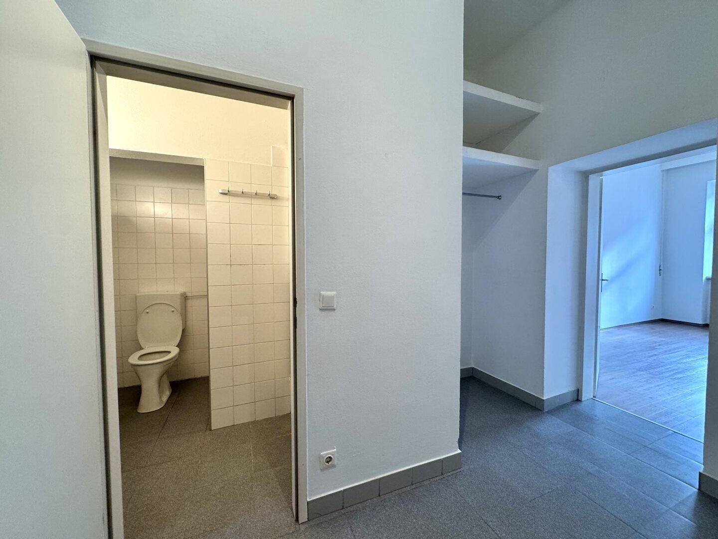 Flur mit Zugang zu einem gefliesten Badezimmer und einem weiteren Zimmer, mit Stauraum.