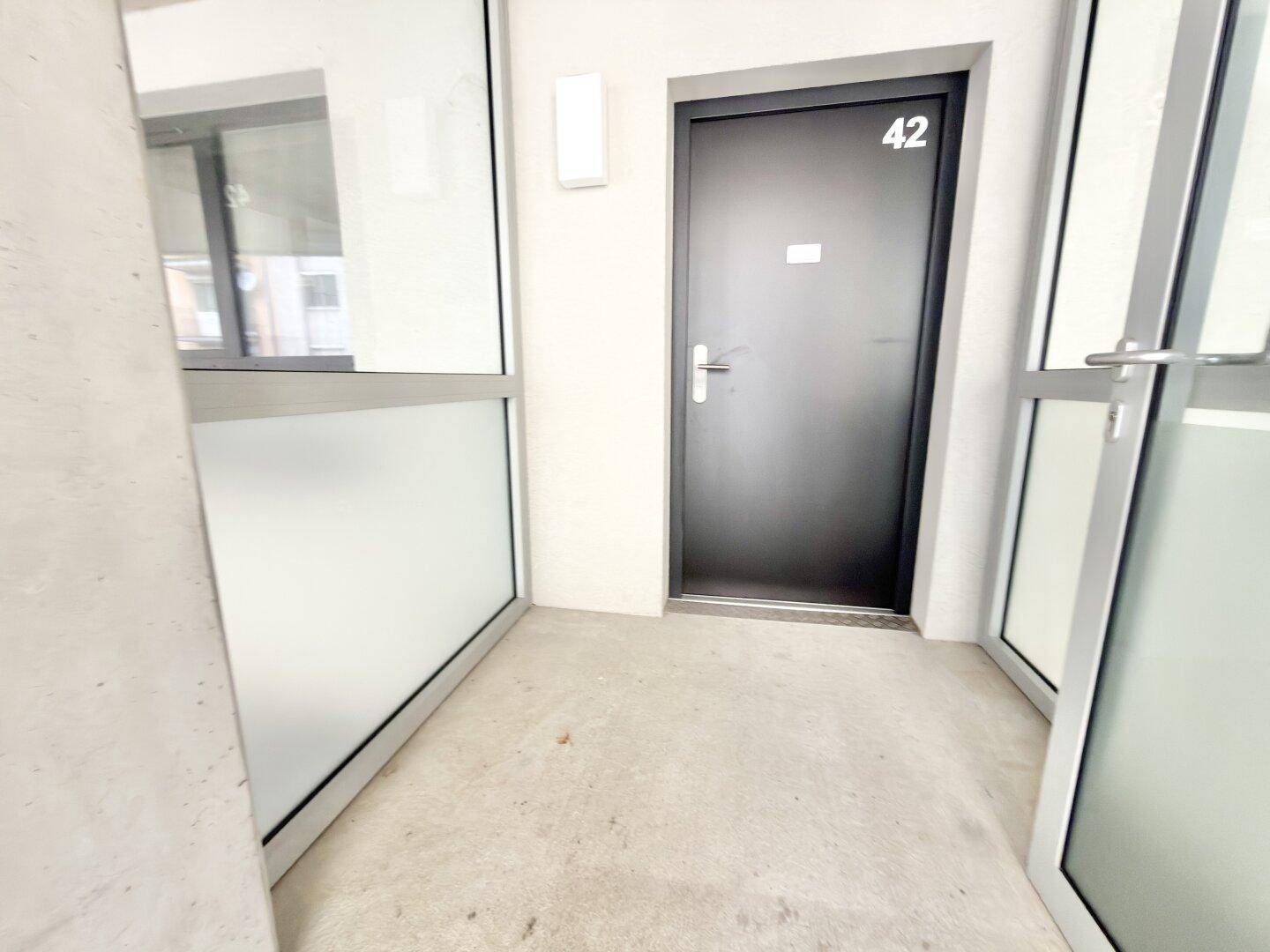 Eingangsbereich einer Wohnung mit schwarzer Tür und der Nummer 42.