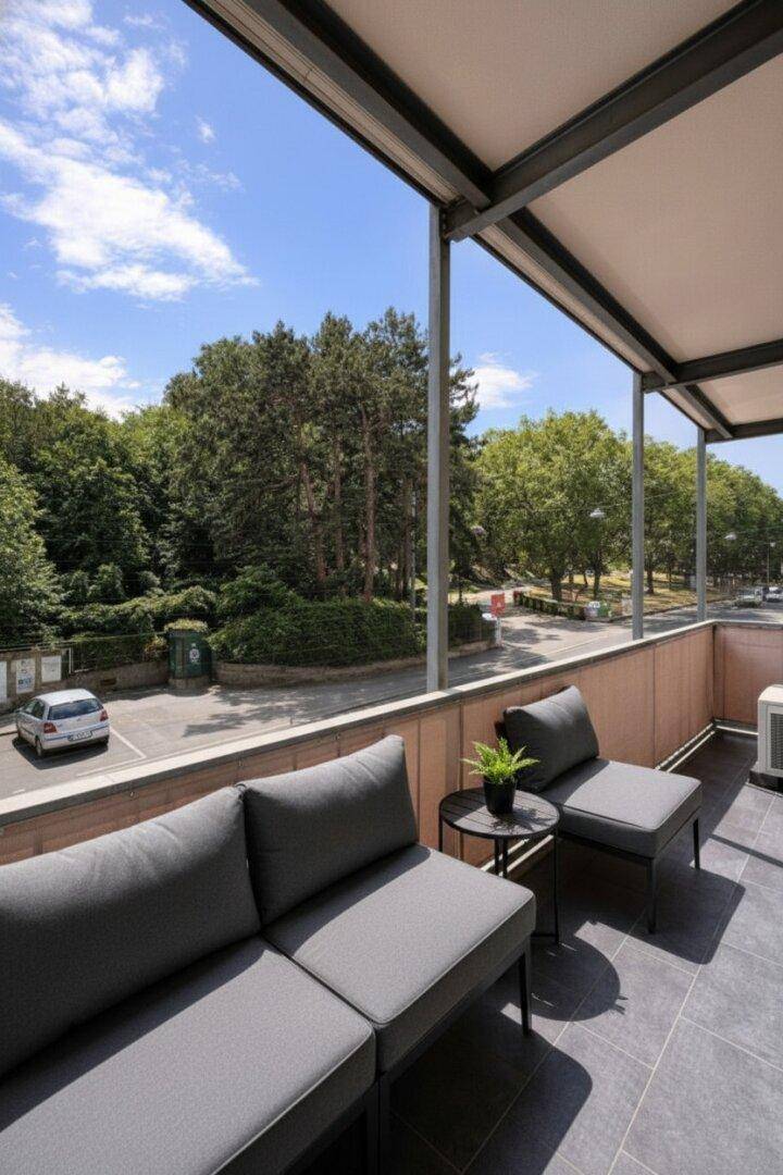Möblierter Balkon mit Blick ins Grüne und auf die Straße, ideal zum Entspannen.