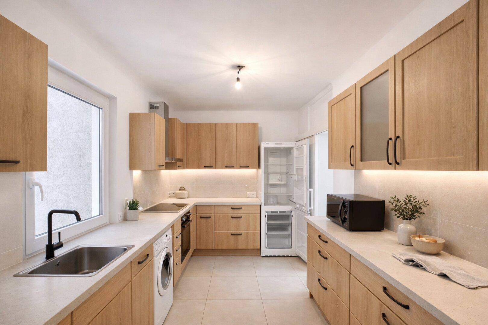 Moderne Küche mit Holzschränken, Fliesenboden und integrierten Geräten, hell und funktional.