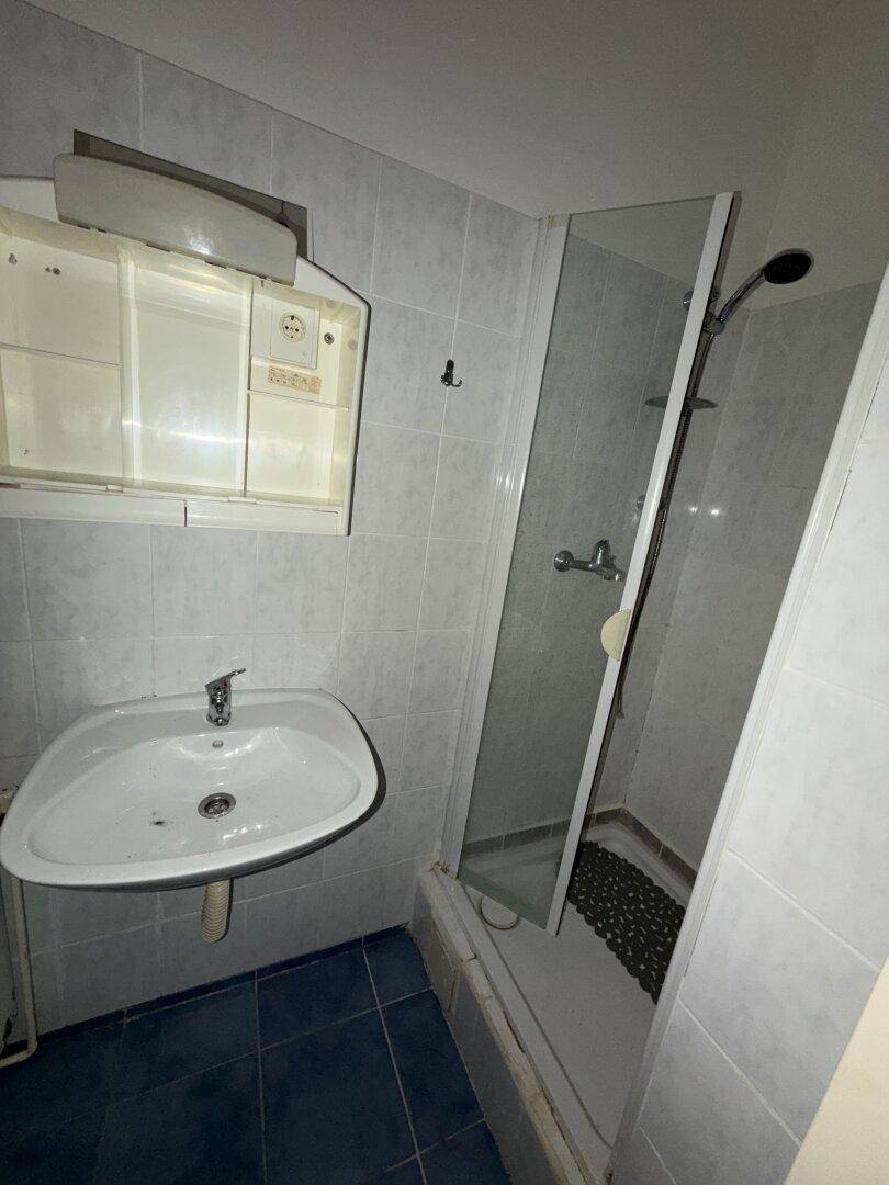 Funktionales Badezimmer mit Duschkabine, Waschbecken und Spiegelschrank.