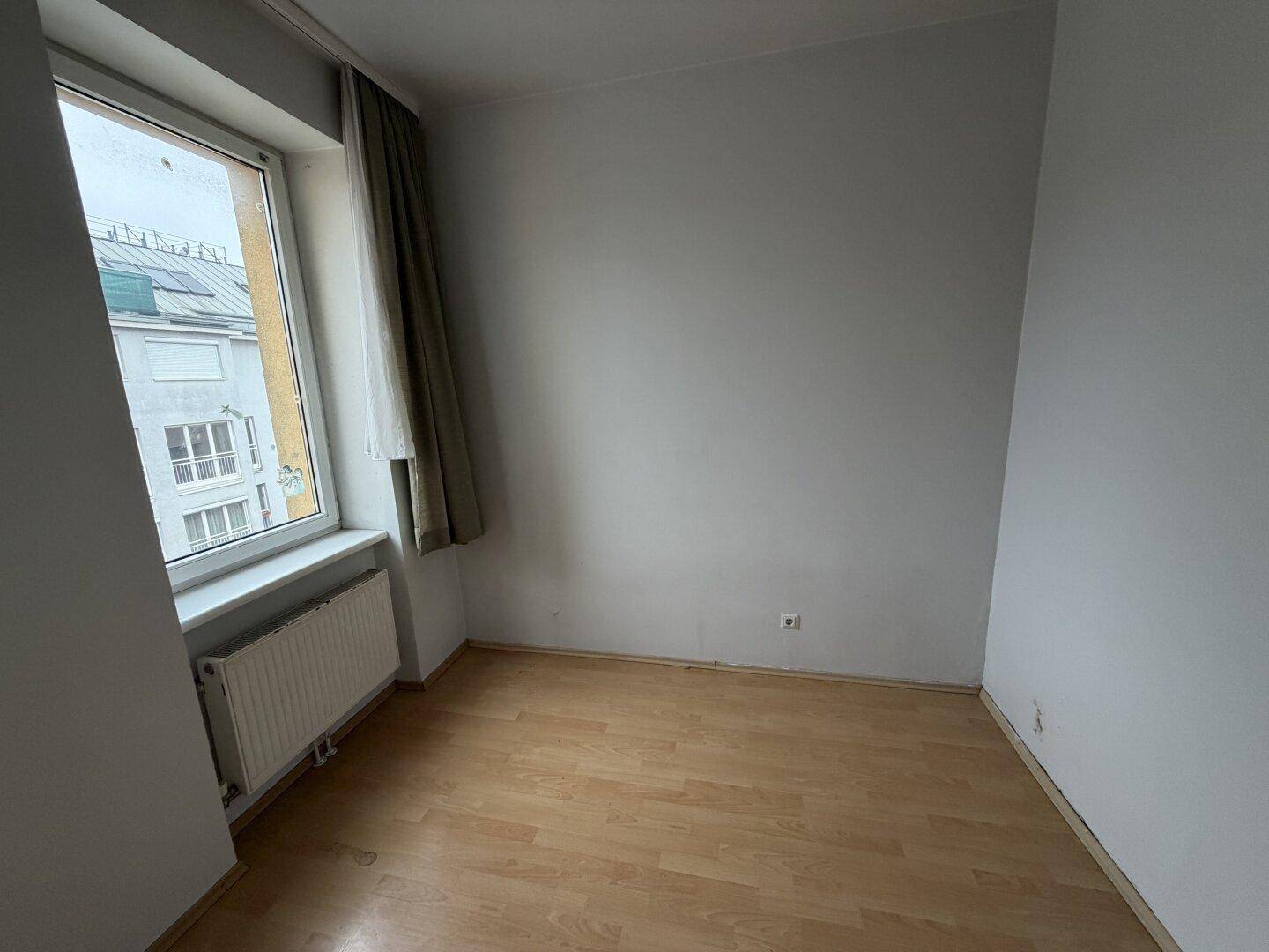 Kleines, helles Zimmer mit Laminatboden und einem Fenster, ideal als Schlaf- oder Arbeitszimmer.