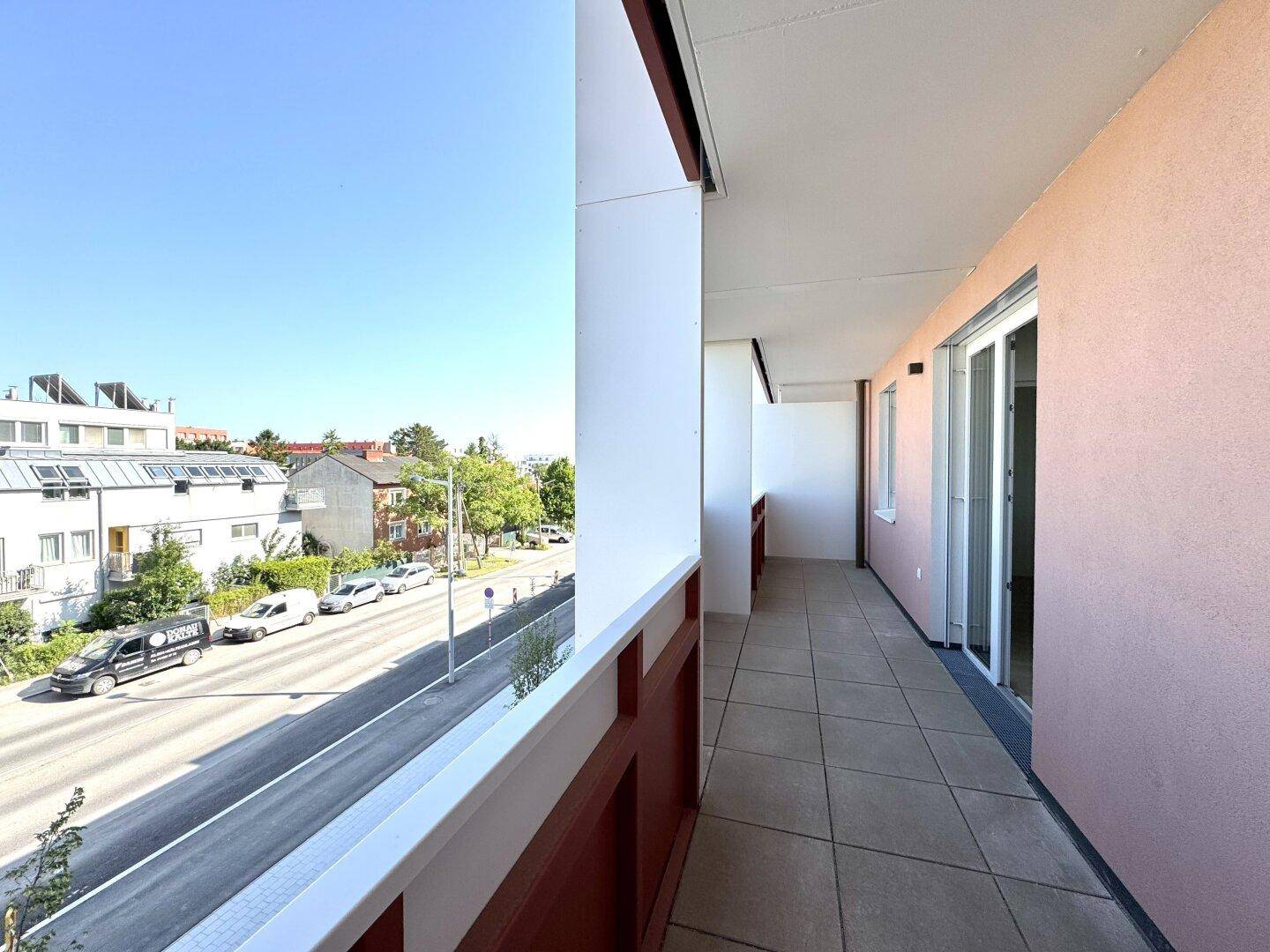 Geräumiger Balkon mit Fliesenboden und Blick auf die Straße und die umliegenden Gebäude.