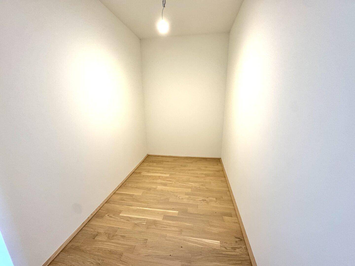 Praktischer Abstellraum mit Parkettboden und weiß gestrichenen Wänden.