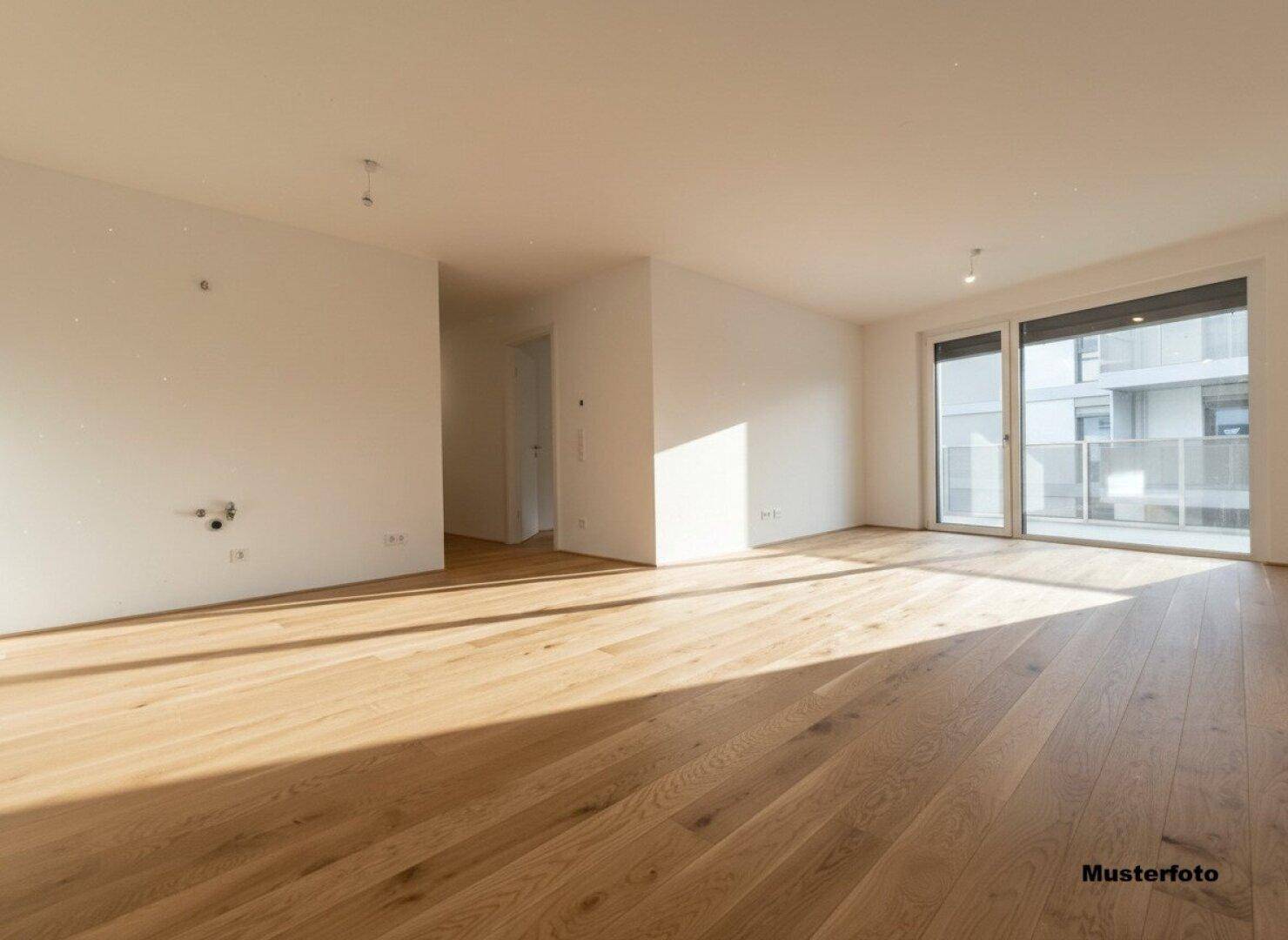 Lichtdurchfluteter Wohnraum mit hellem Holzboden und Zugang zu einem Balkon.