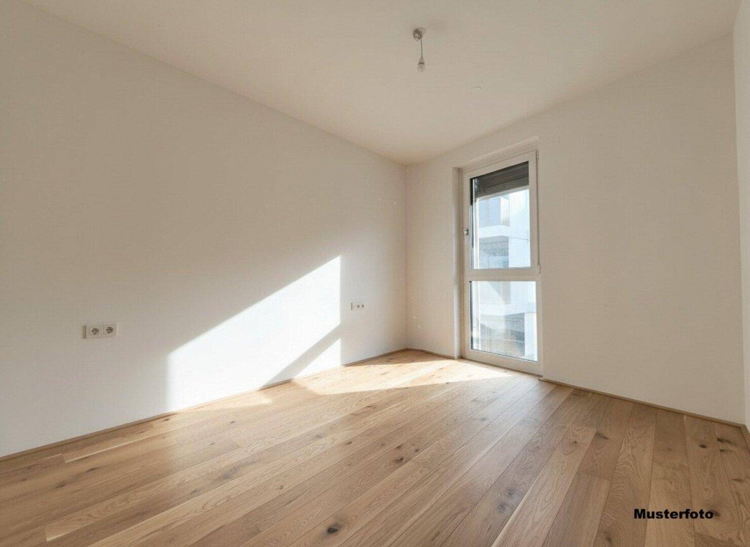 Helles, leeres Schlafzimmer mit Holzboden und einem Fenster, das viel Tageslicht hereinlässt.