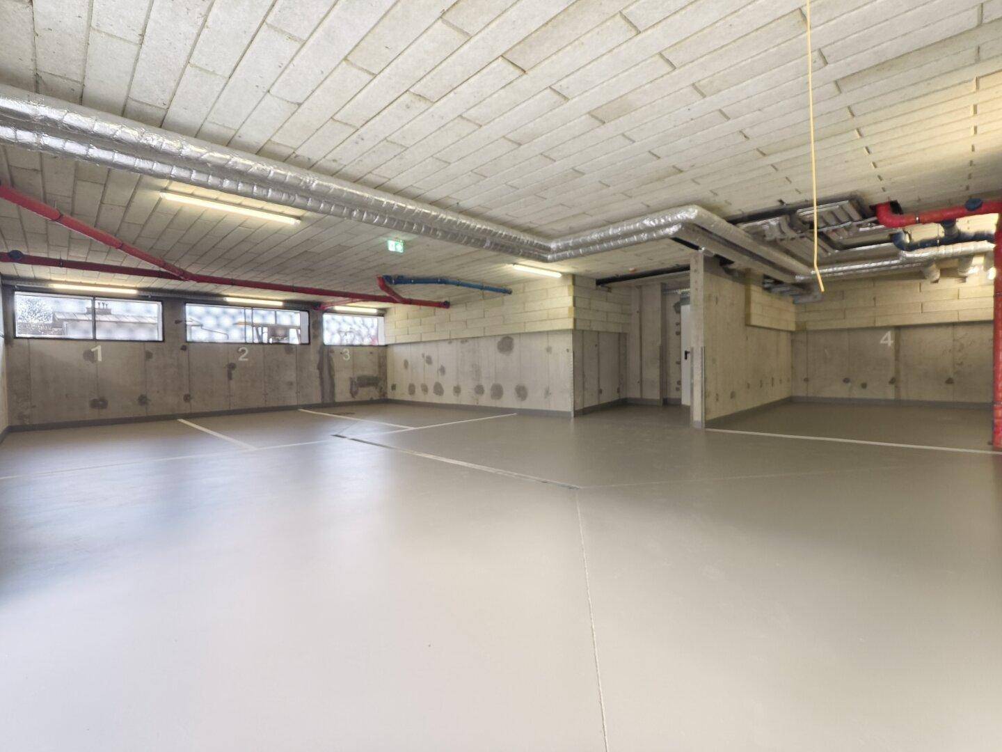Geräumige Tiefgarage mit markierten Stellplätzen und sichtbaren Installationen.
