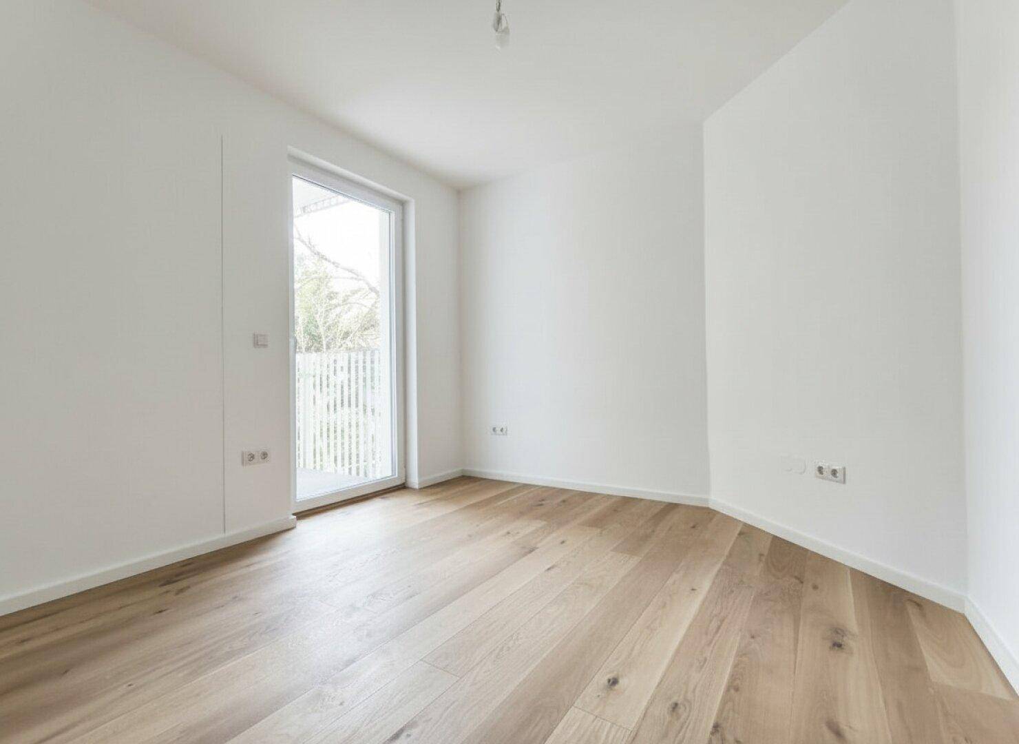 Gemütliches Zimmer mit hellem Holzfußboden und Zugang zu einem kleinen Außenbereich.