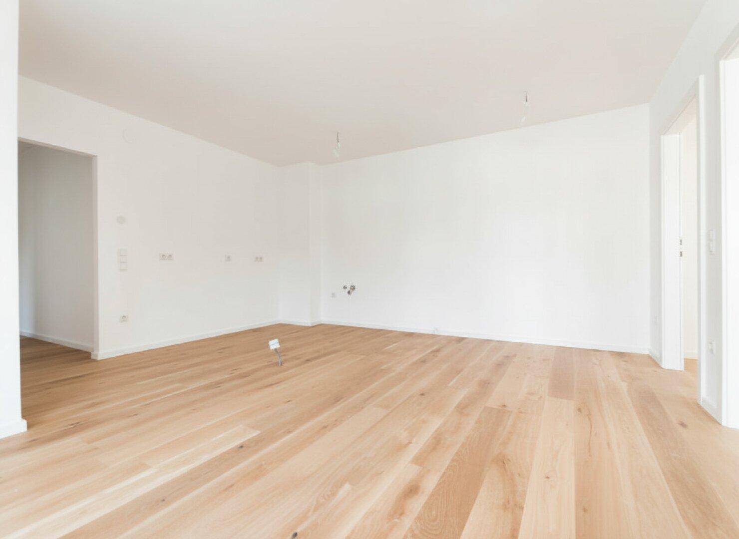Lichtdurchfluteter Raum mit elegantem Holzparkett und klaren Linien, ideal für individuelle Gestaltung.