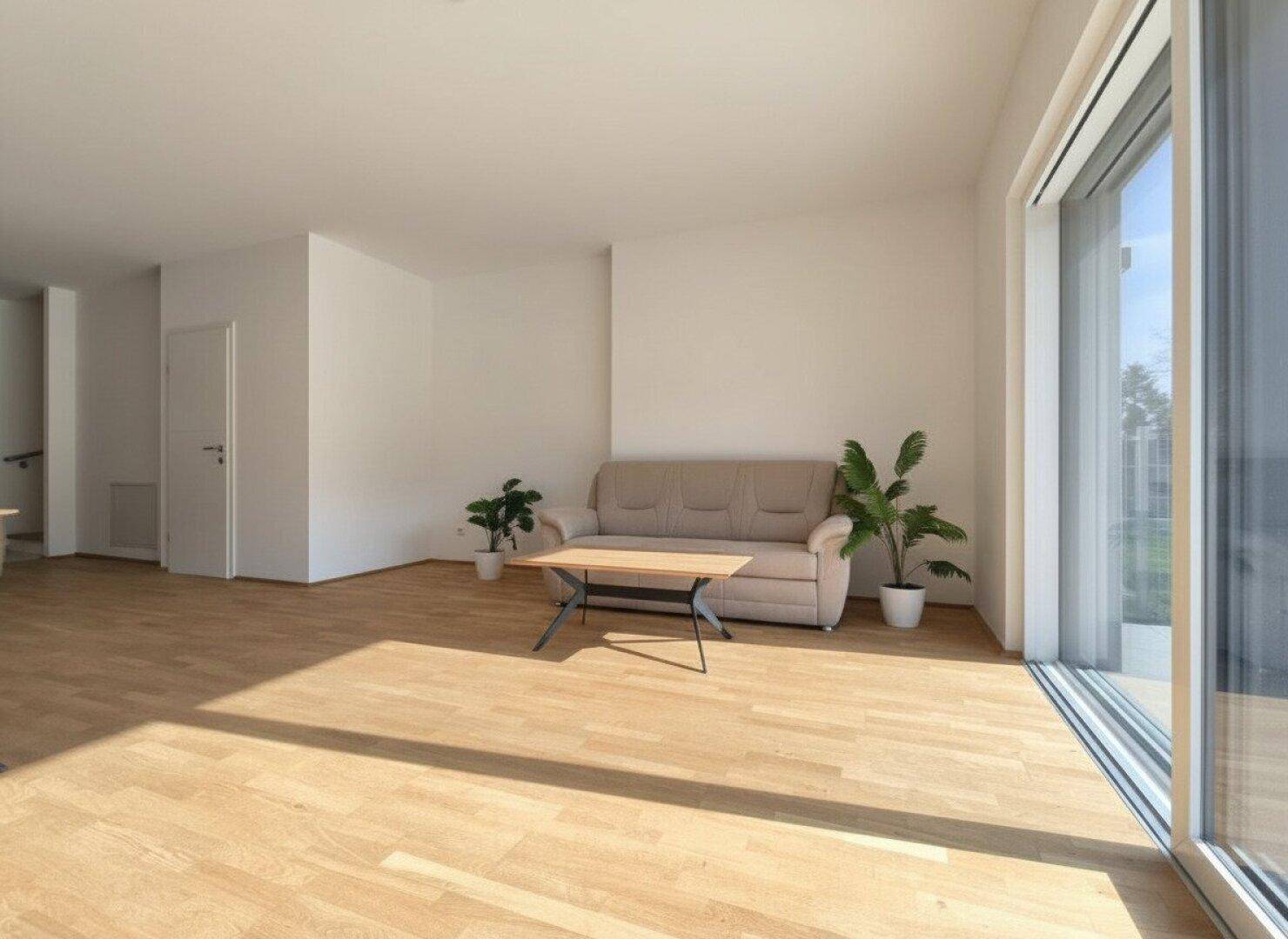 Gemütlicher Wohnbereich mit beigem Sofa, Holzboden und viel Tageslicht durch große Fenster.